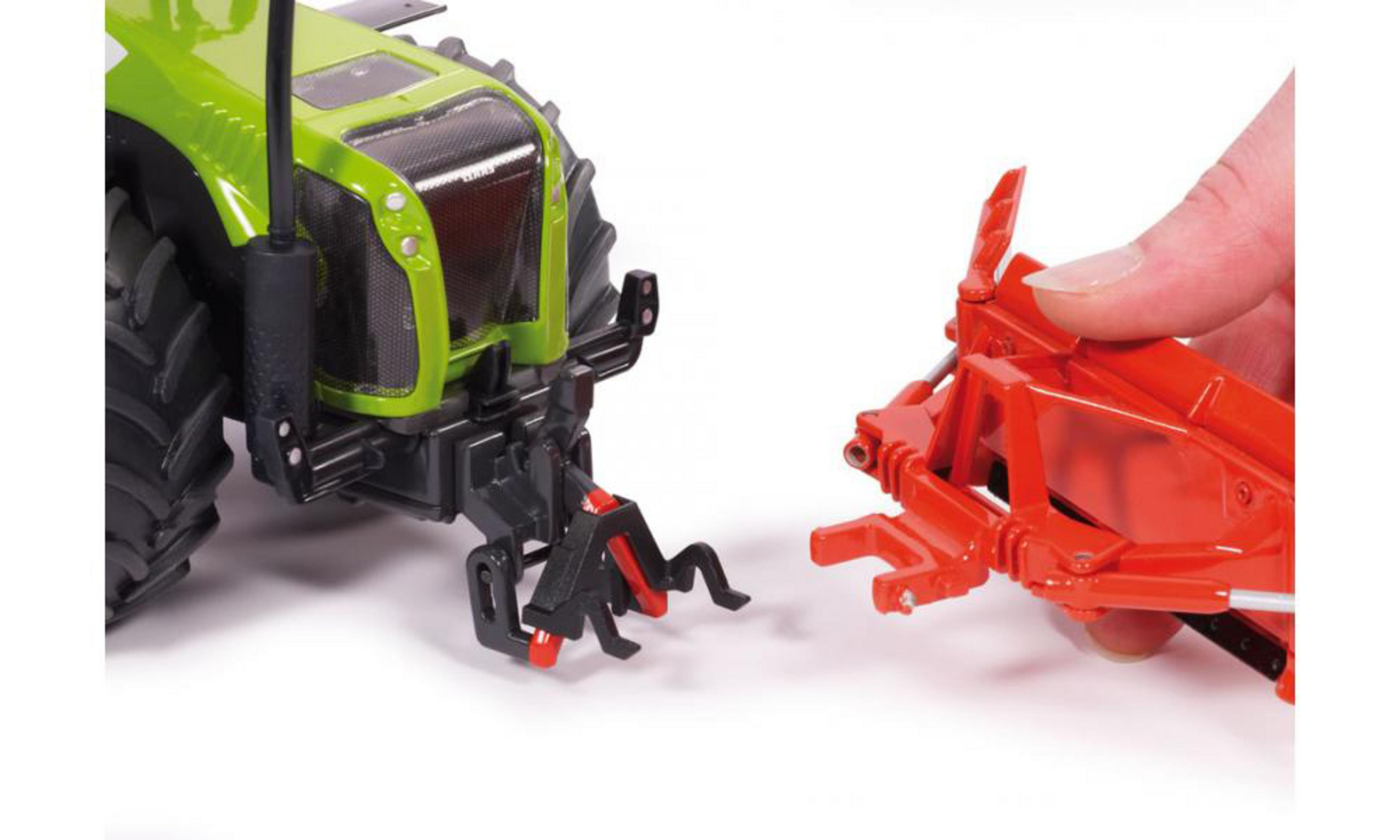 Spielzeugtraktor und oranger Anbau, die von einer Hand verbunden werden. Grüne und rote Farben.