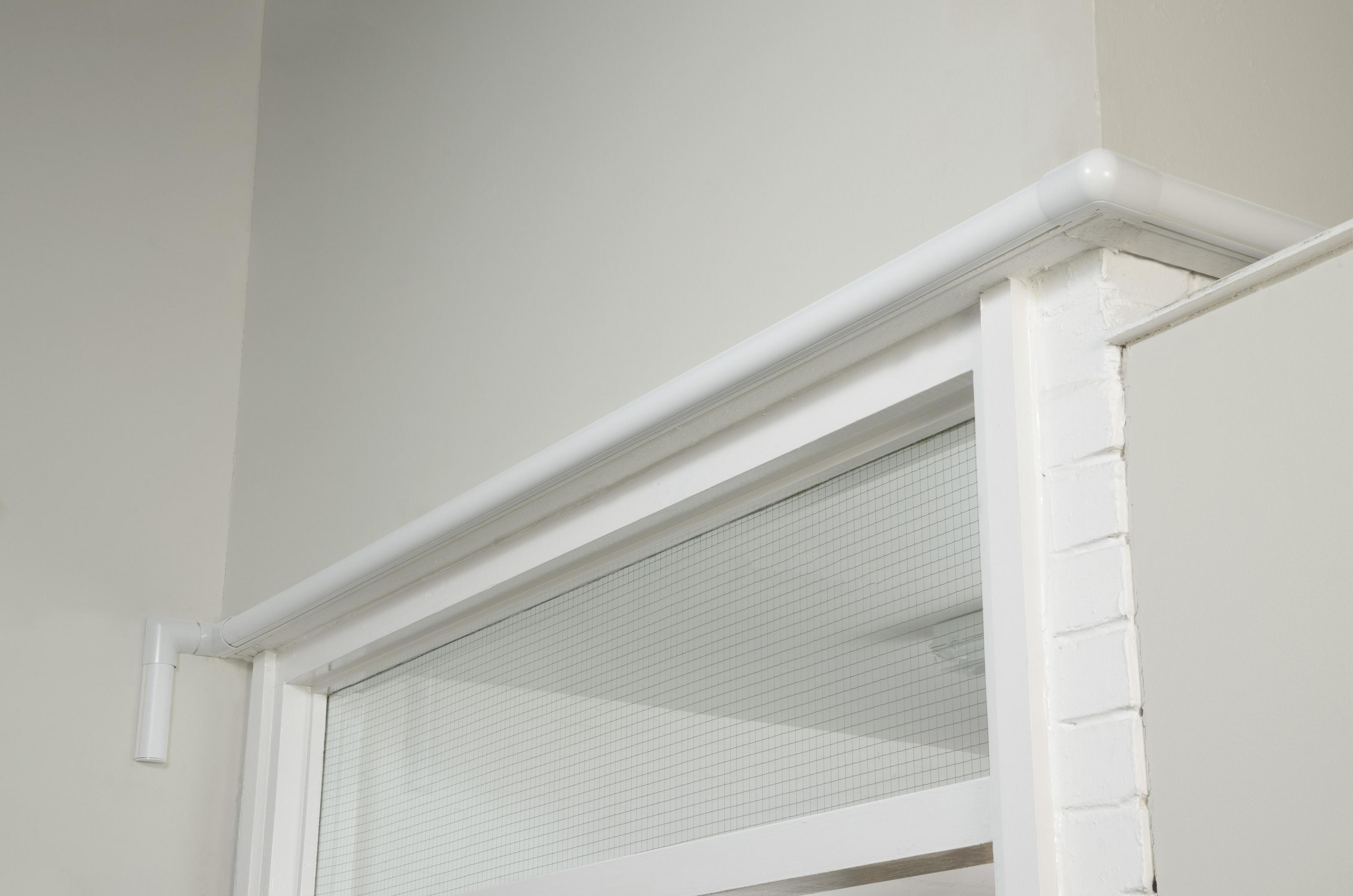 Ein weißes Fenster und Rahmen mit weißer Verkleidung und einer weißen Wand, mit einem Gittermuster auf dem Glas.