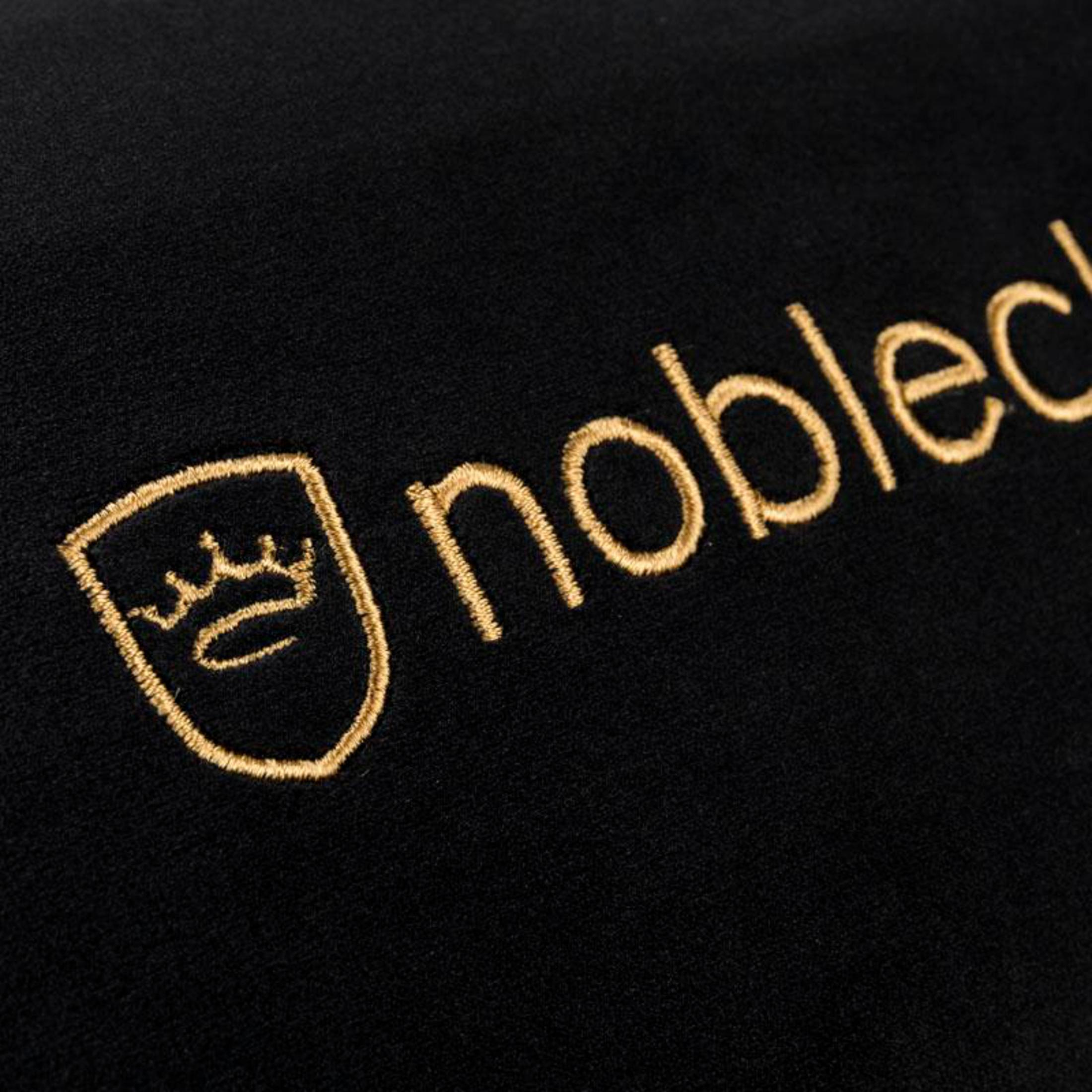 Schwarzer Stoff mit goldgesticktem Logo einer Krone und dem Wort noble.