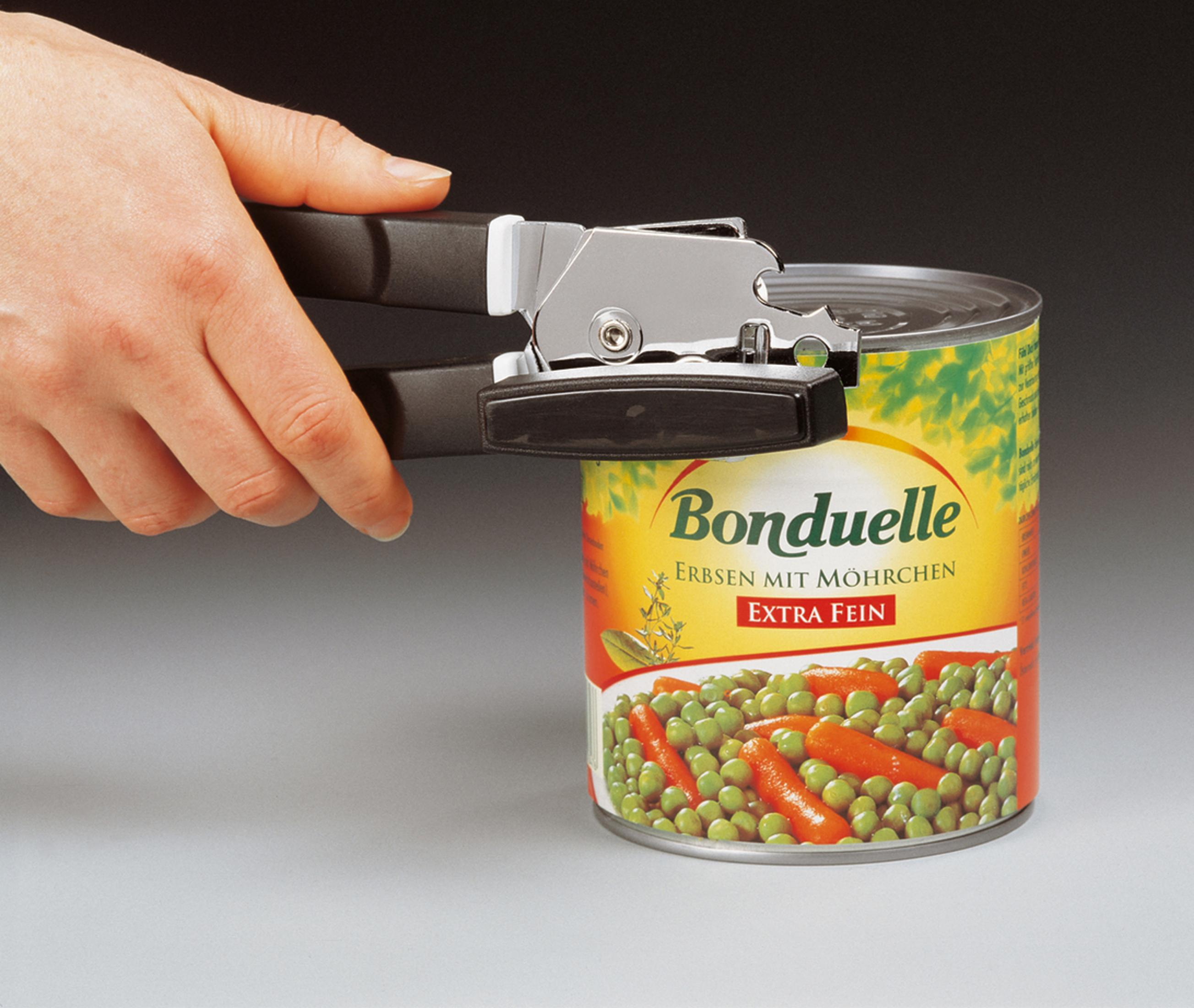 Mano che usa un apriscatole su una lattina di verdure. Lattina verde e arancione.