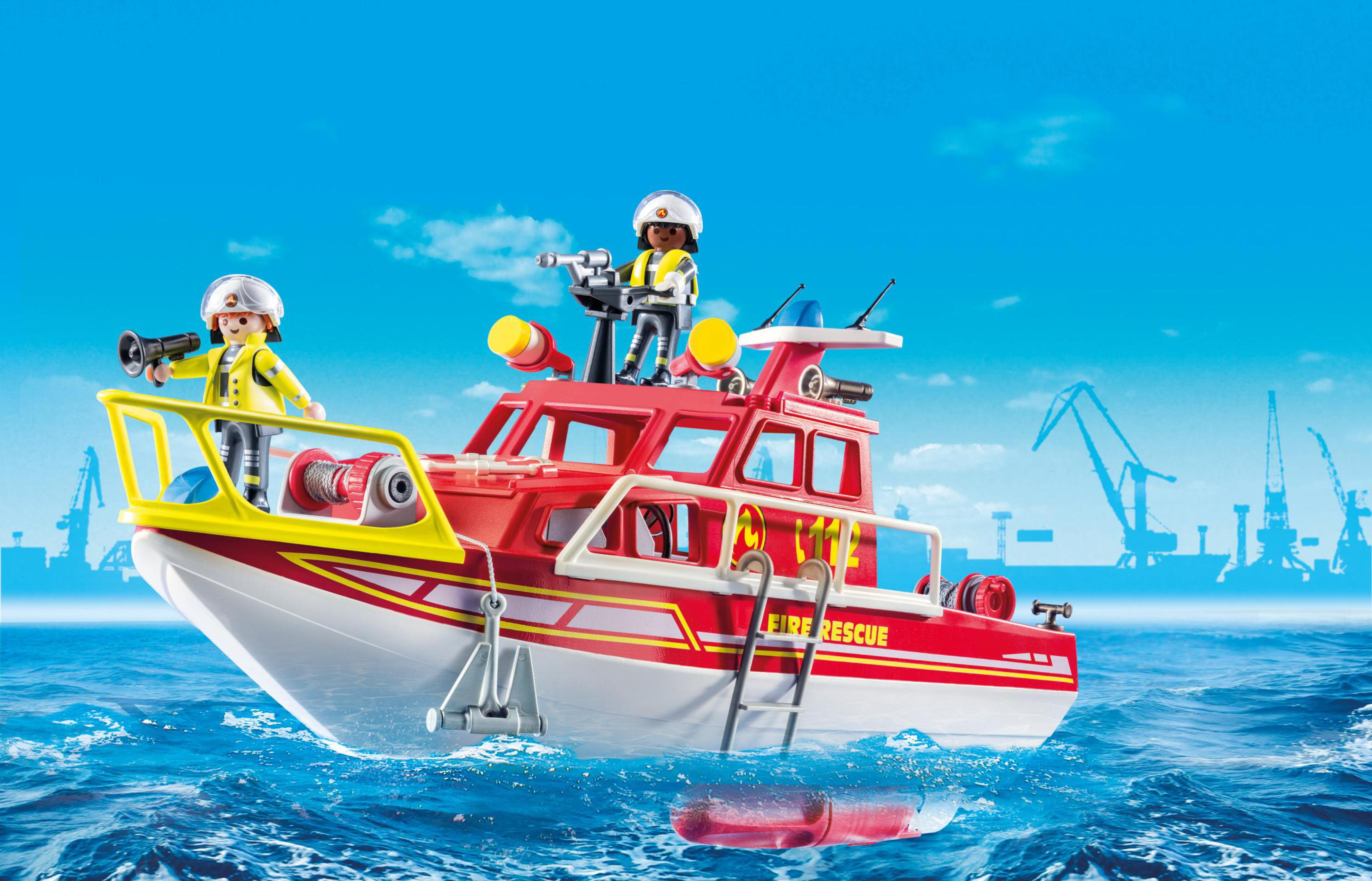 Spielzeug-Feuerwehrboot mit zwei Feuerwehrleuten und einer Rettungsleiter, auf Wasser.