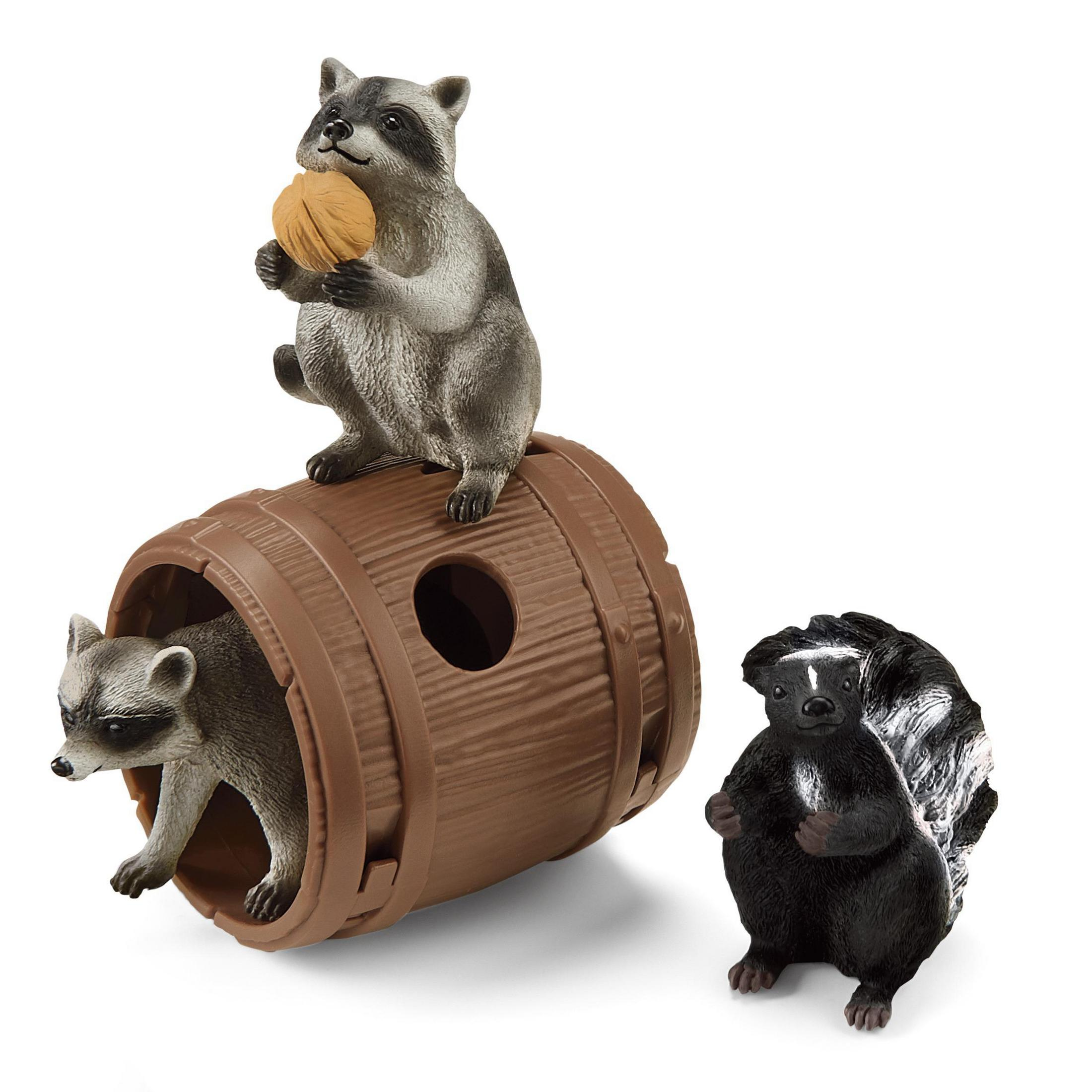 Spielzeug Waschbären, Stinktier. Waschbär auf Fass, Nuss haltend. Stinktier sitzend. Weißer Hintergrund.