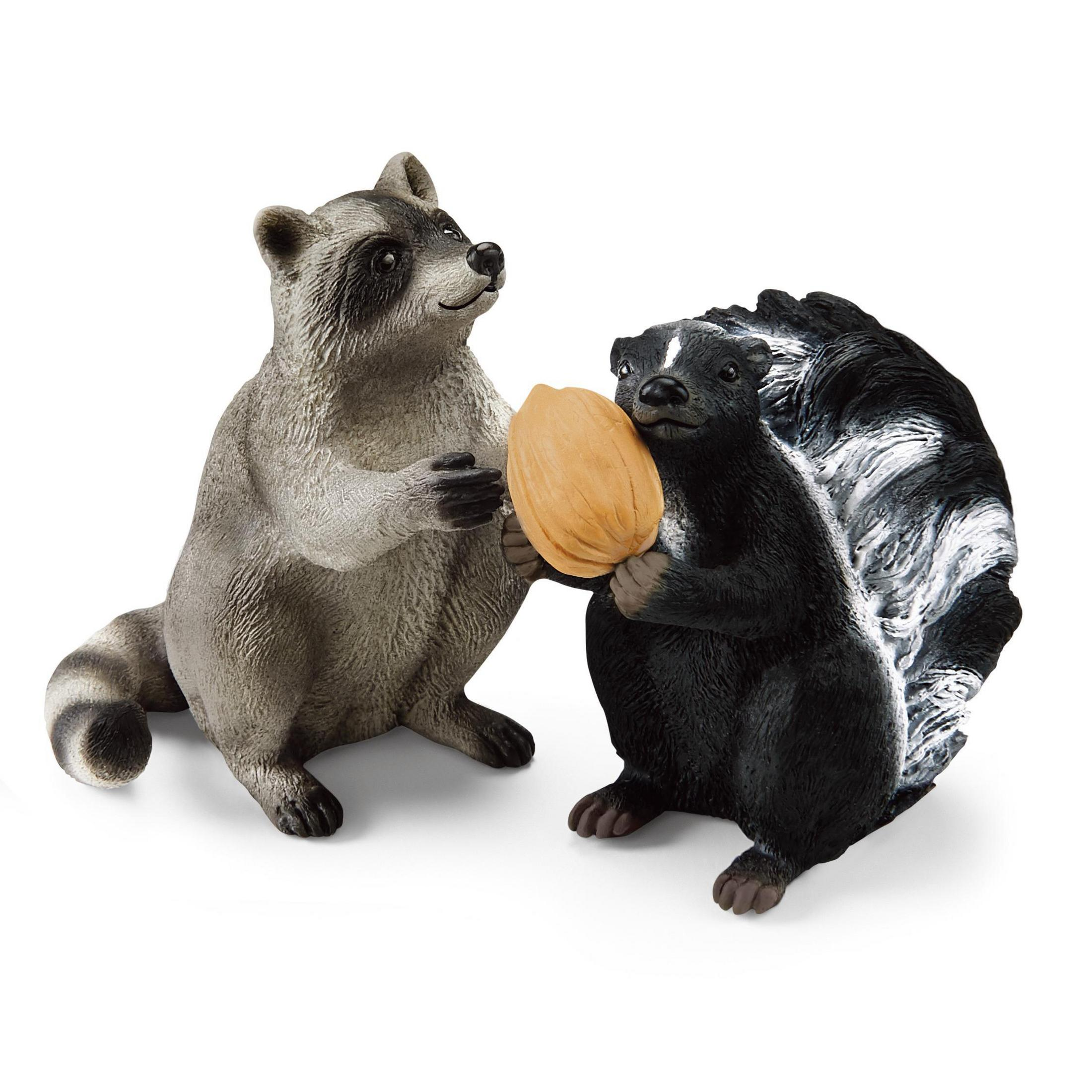 Zwei Spielzeugtiere, ein Waschbär und ein Stinktier, halten eine Nuss. Sie sind auf weißem Grund.