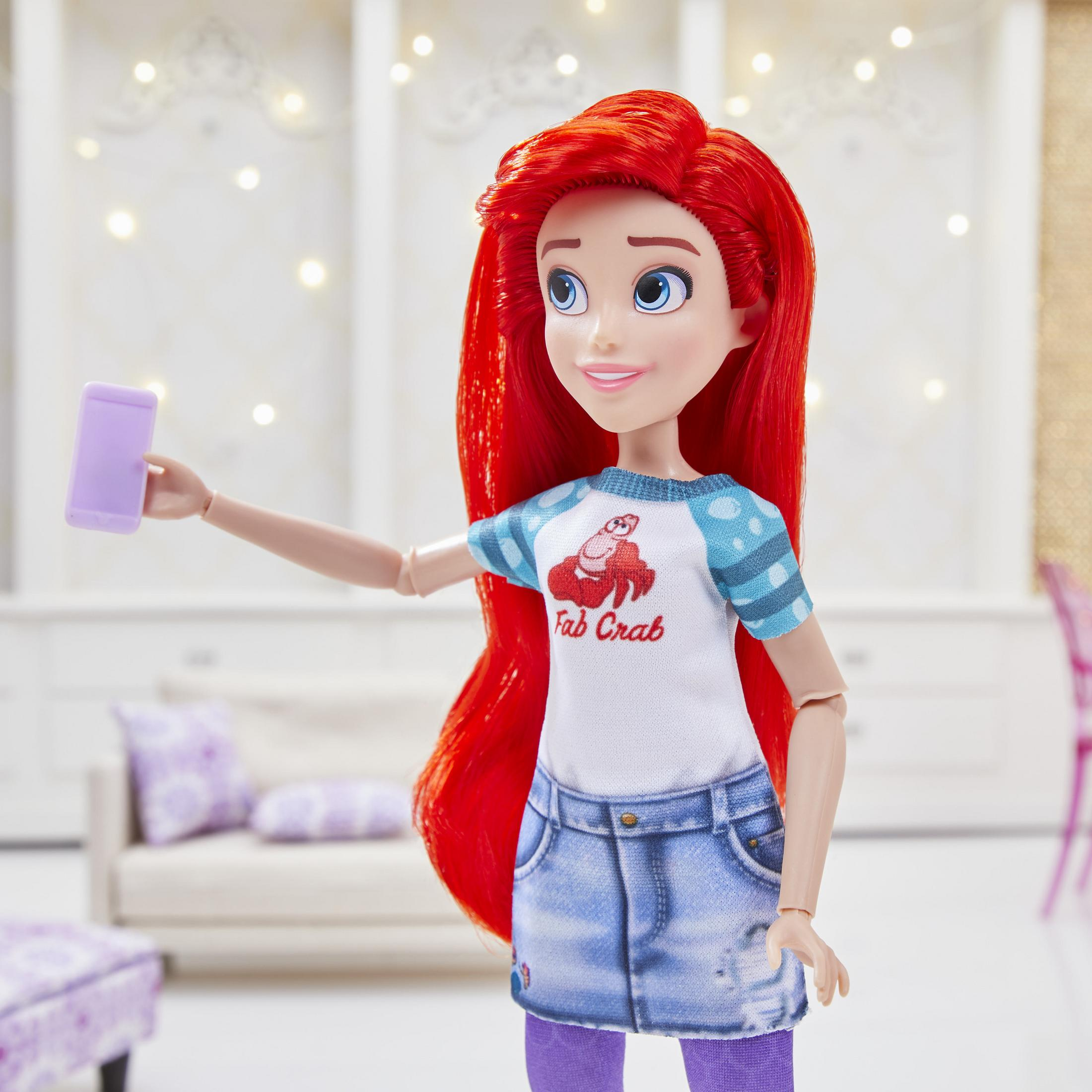 Ariel-Puppe macht ein Selfie. Sie trägt ein weißes Hemd mit Krabbe und Jeansrock, rote Haare und lila Leggings.