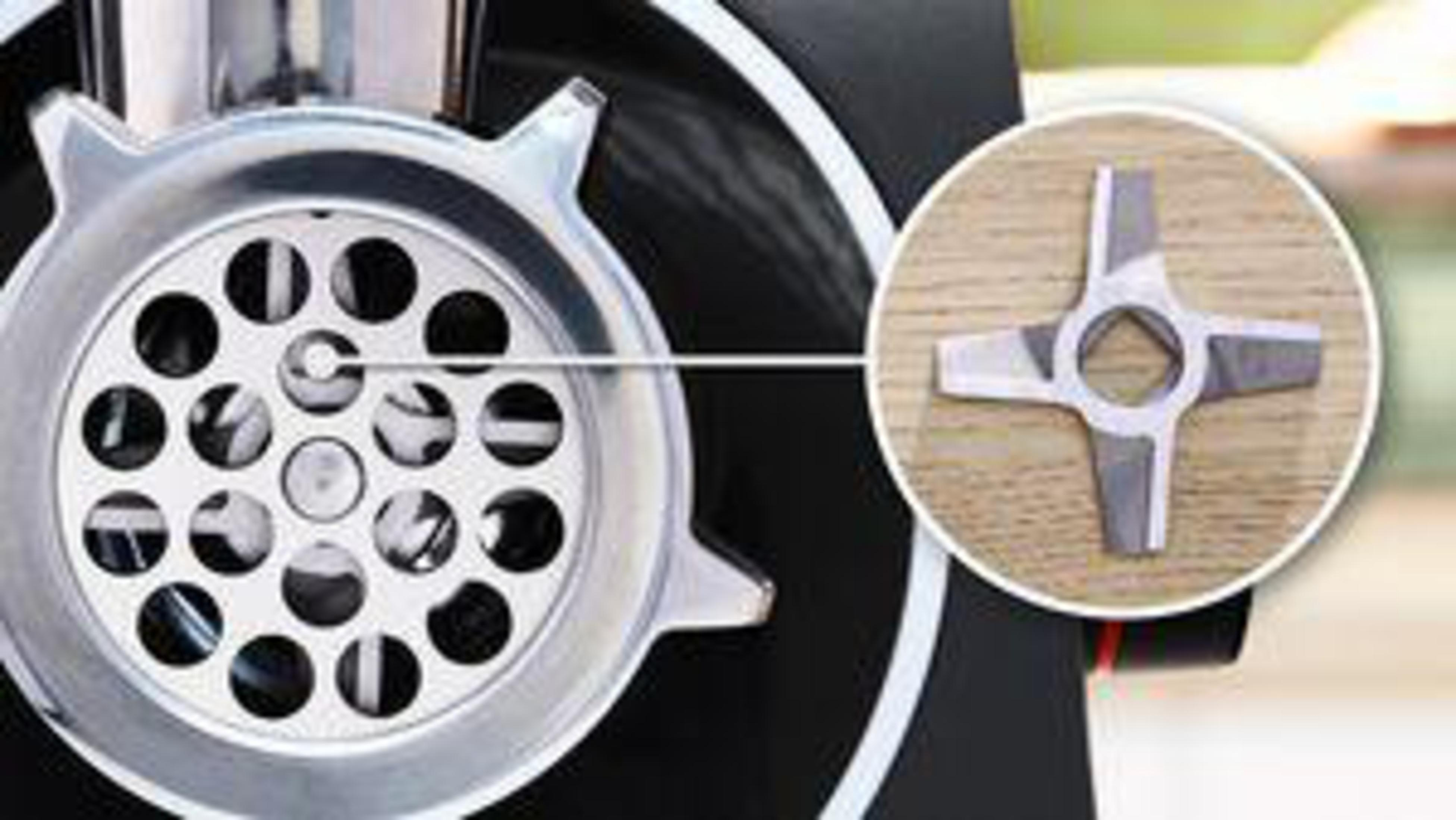 Maszynka do mięsa ze zbliżeniem na płytę tnącą i ostrze, pokazującym otwory i szczegóły ostrza.