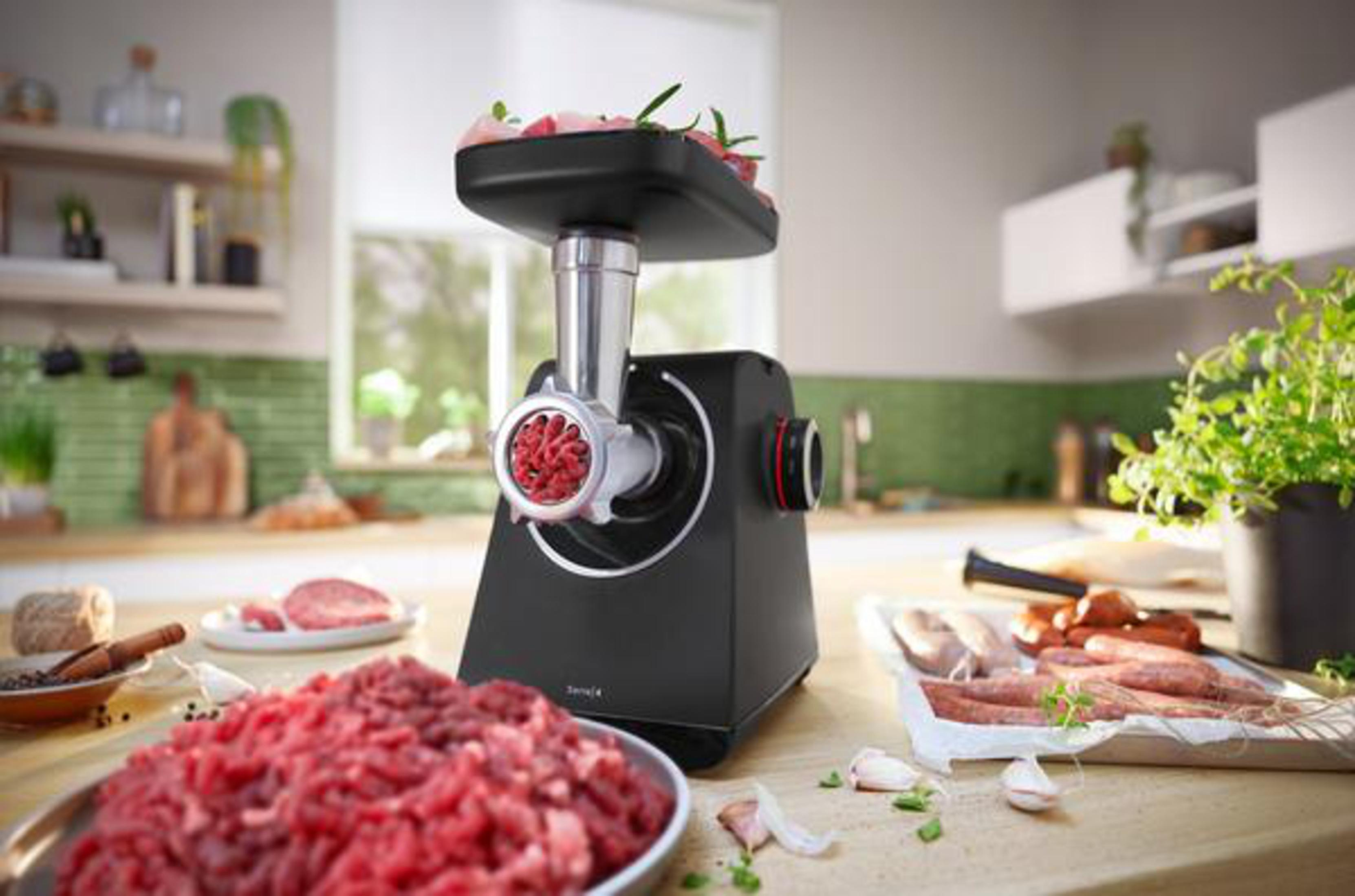 Czarna maszynka do mięsa z surowym mięsem i tłem kuchni.