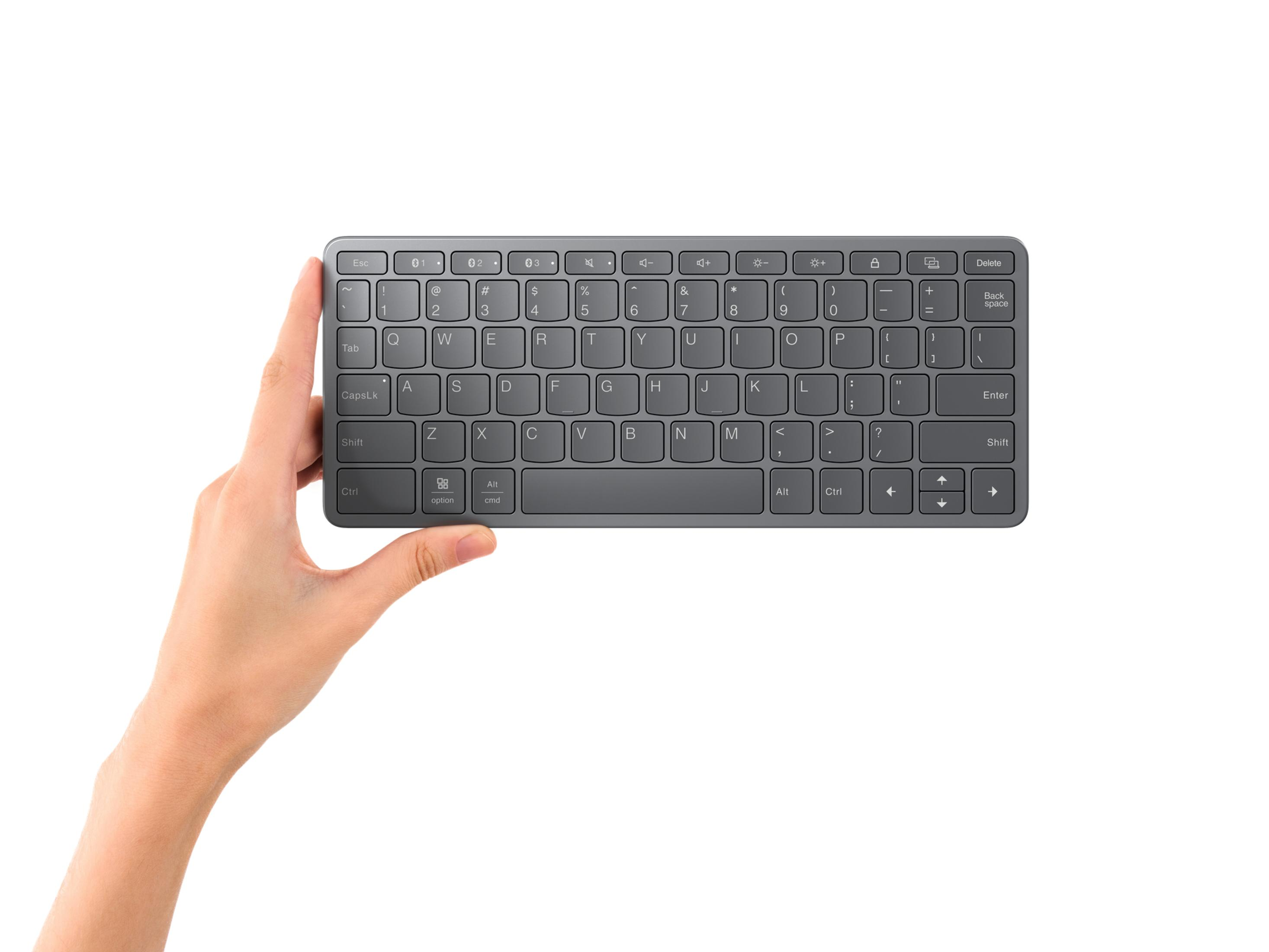 Una mano sosteniendo un teclado gris contra un fondo blanco.