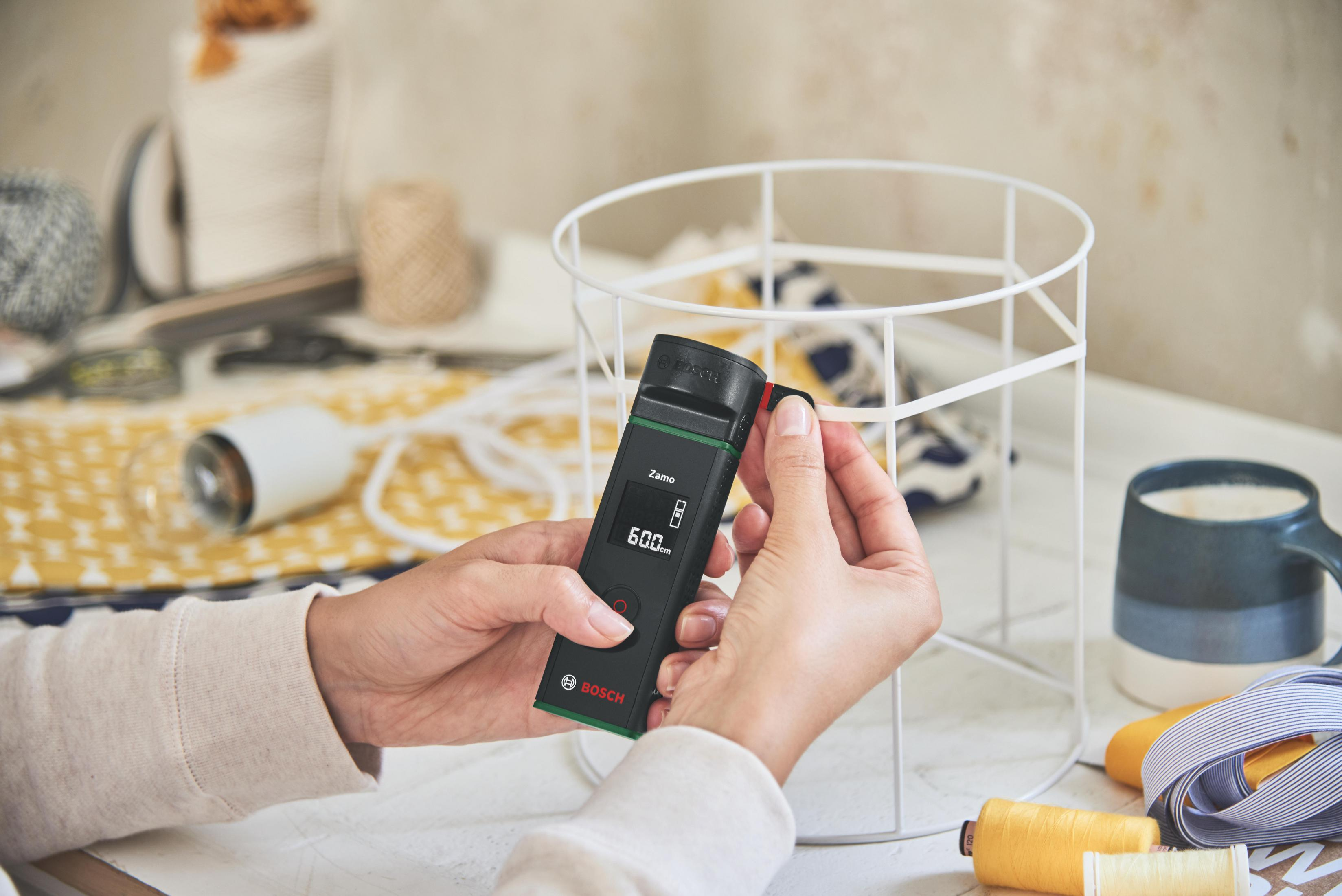 Eller, siyah bir telemetre ile metal bir lamba çerçevesini ölçüyor.