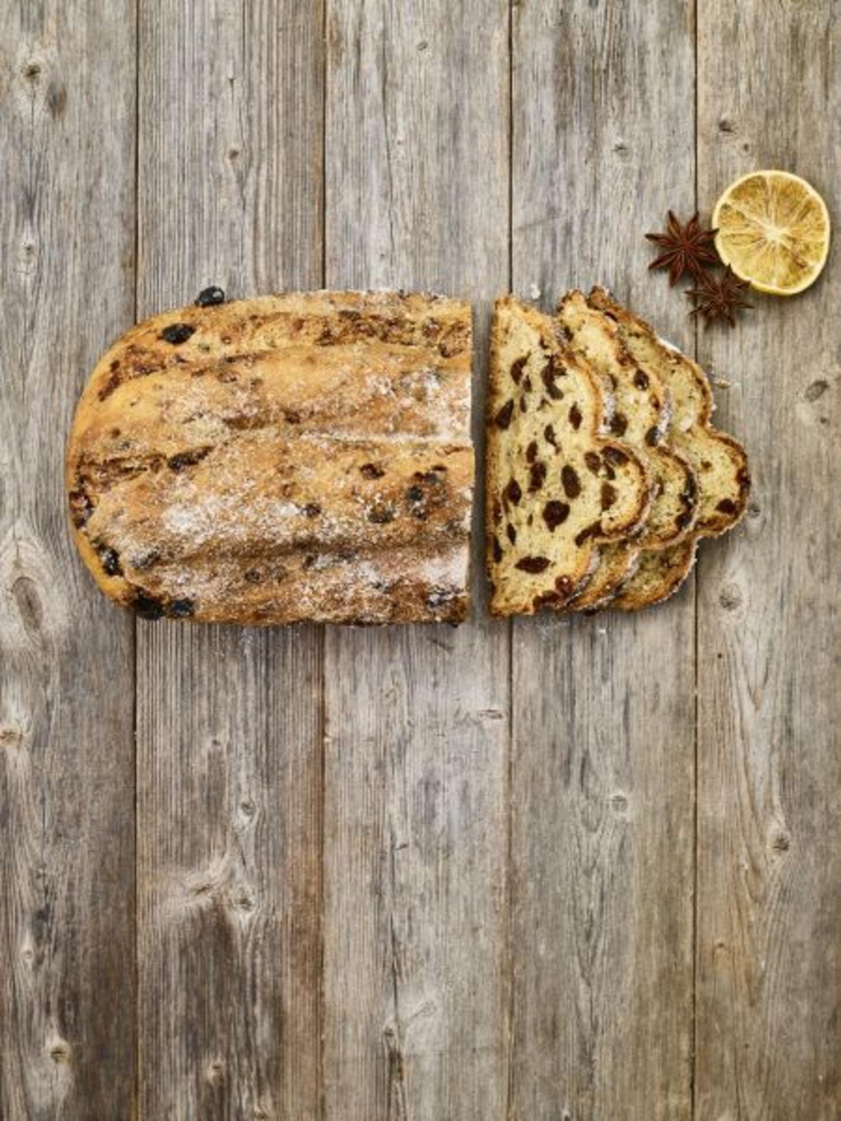 Stollenbrot, geschnitten und auf einer Holzoberfläche mit Gewürzen angeordnet.