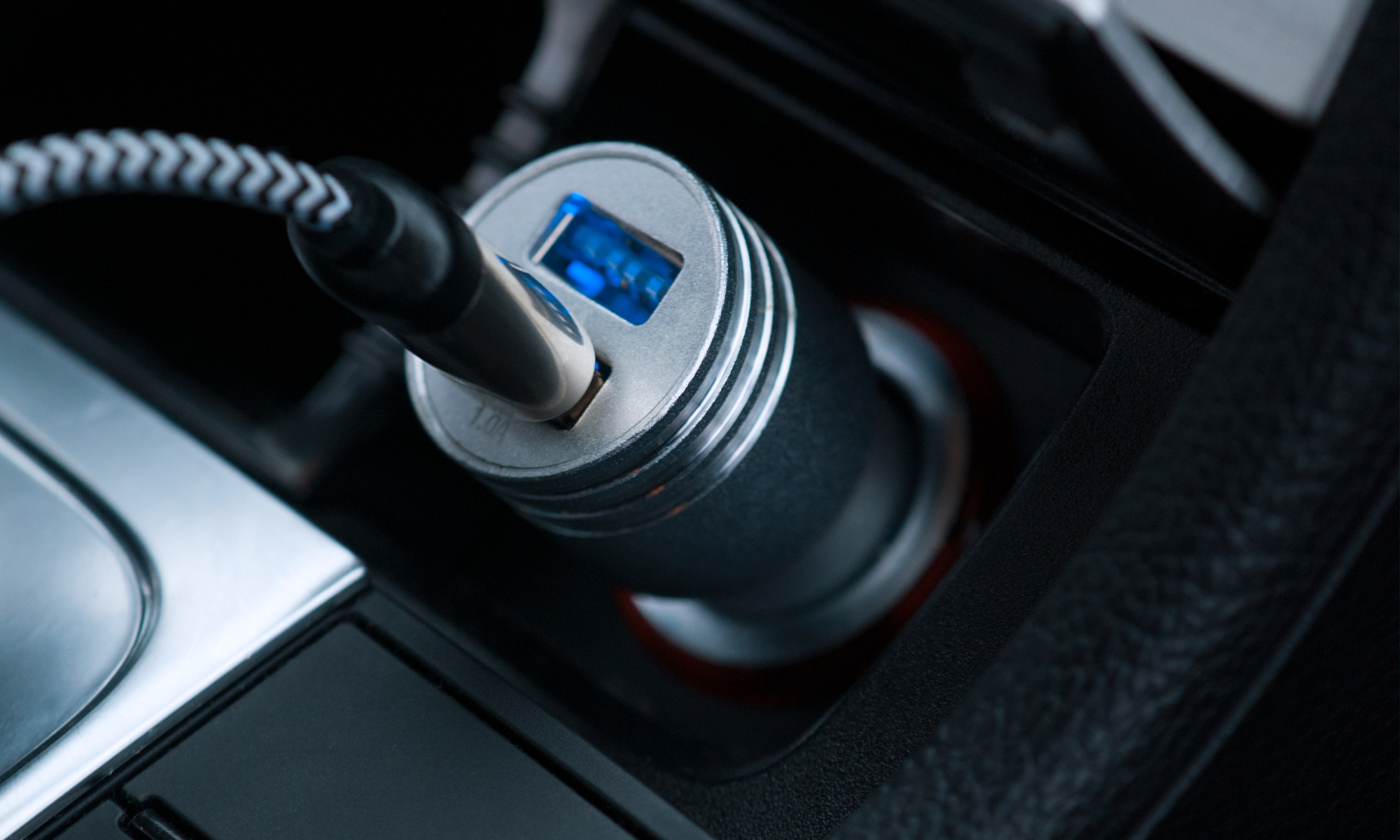 Un caricabatterie per auto collegato alla presa di corrente di un'auto. Ha una porta USB con luce blu.