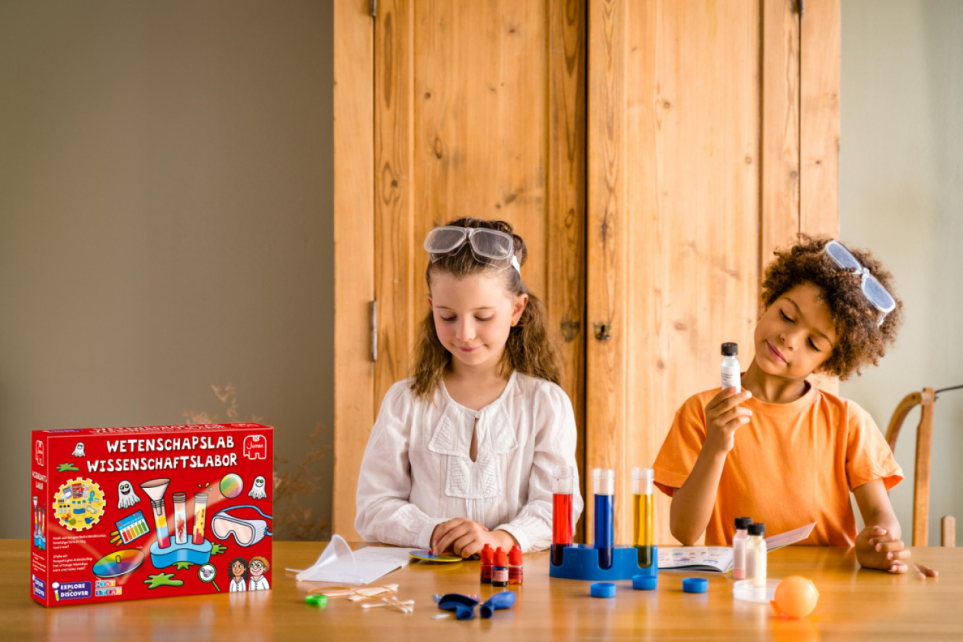 Zwei Kinder machen ein wissenschaftliches Experiment an einem Tisch mit einem Wissenschafts-Set und Reagenzgläsern.