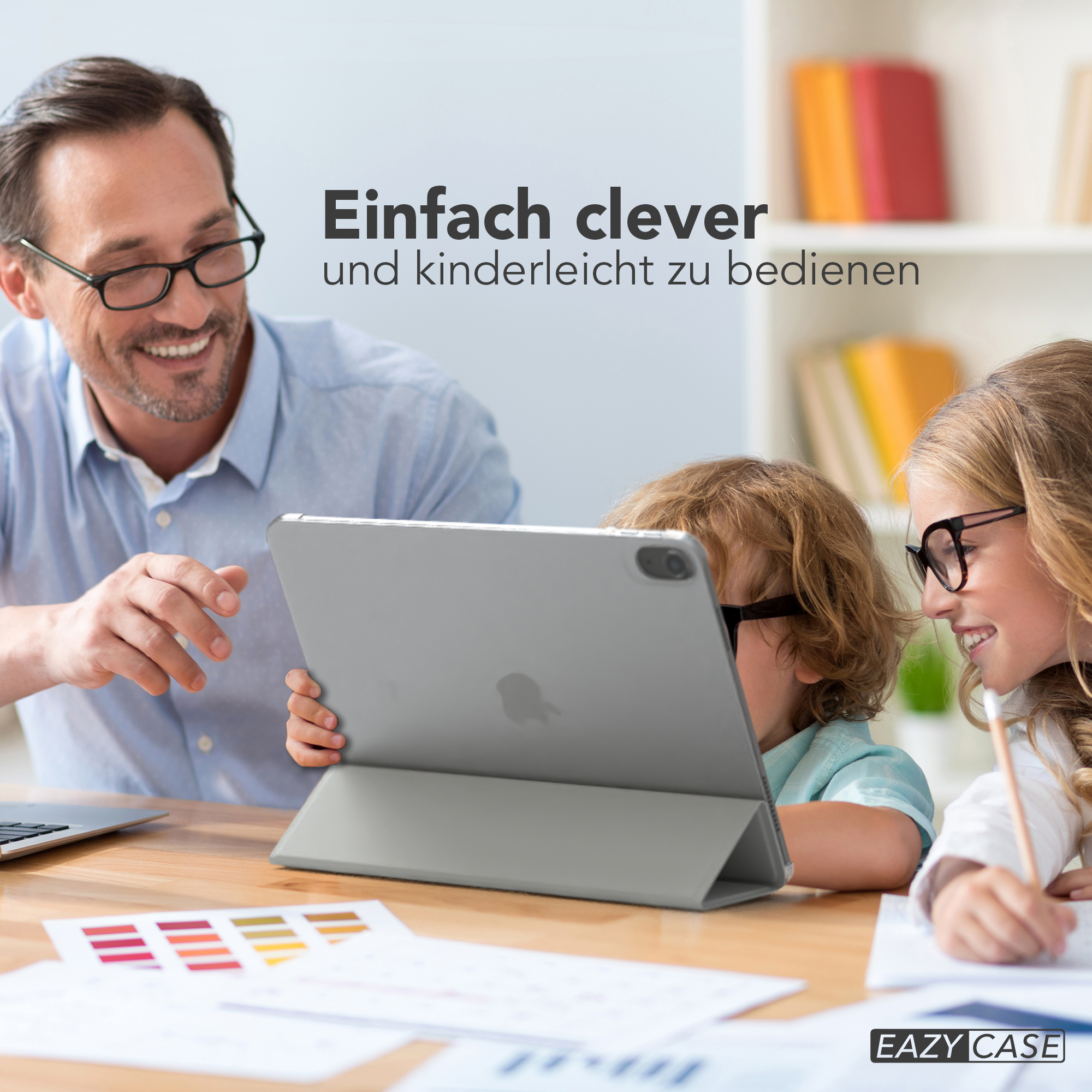 Ein Vater und zwei Kinder betrachten ein iPad auf einem Holztisch.