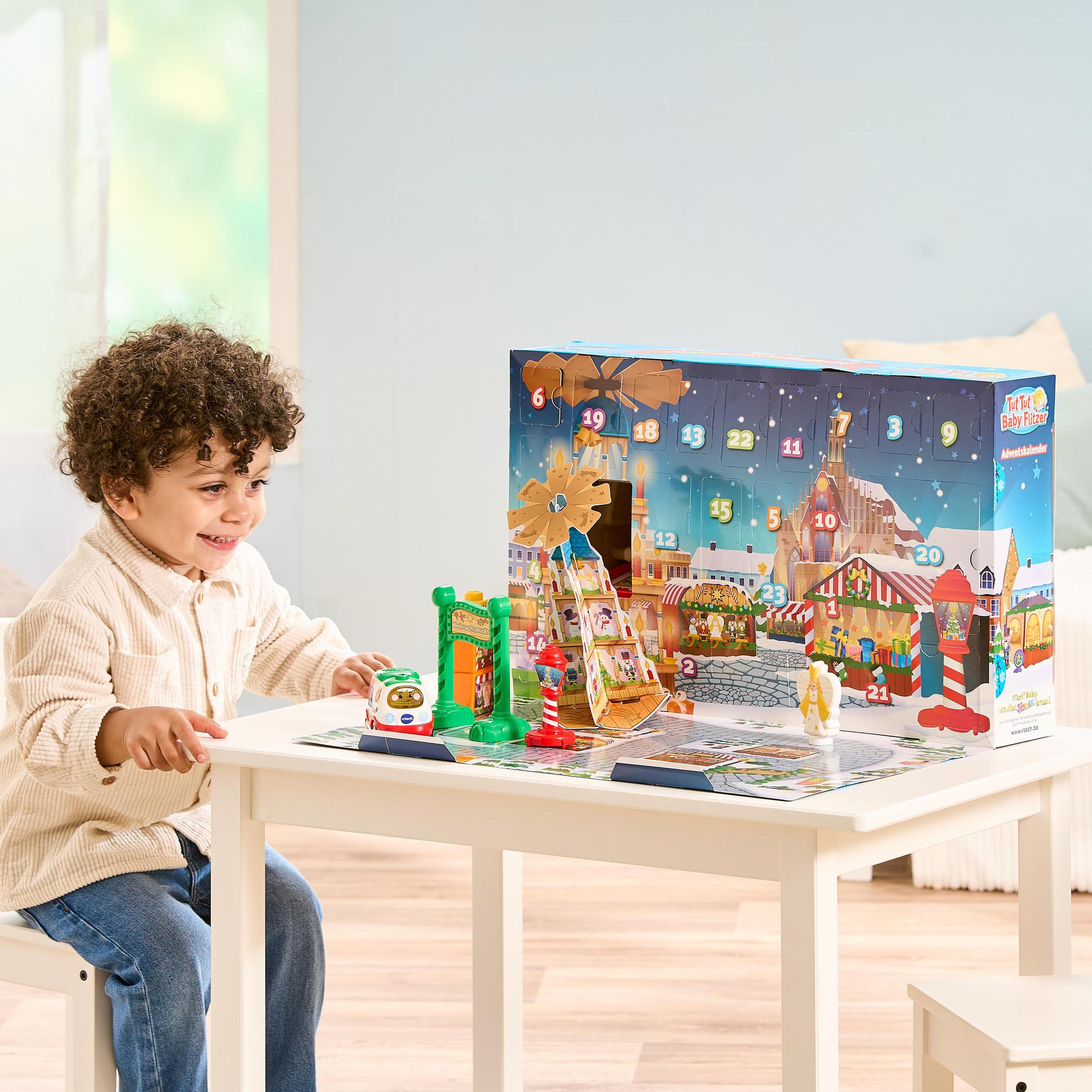 Ein Junge spielt mit einem Adventskalender. Ein Tisch mit Spielzeug in einem Raum.