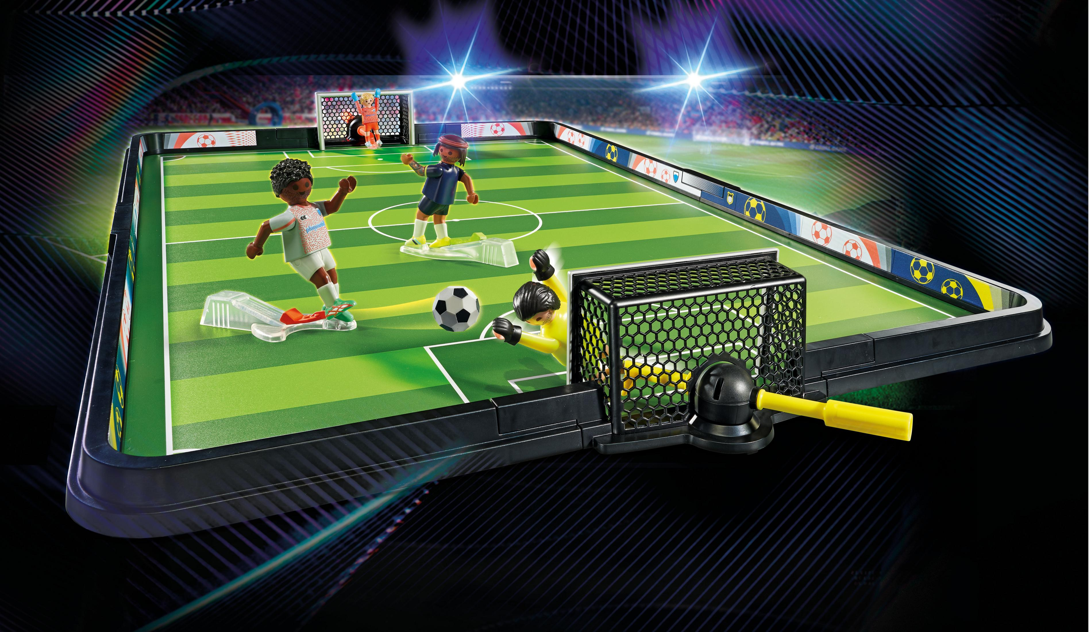 Zabawka boisko do piłki nożnej z zawodnikami, bramkami i piłką w powietrzu.