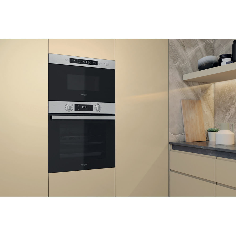 Microonde e forno a incasso in un mobile beige, con parete in marmo.