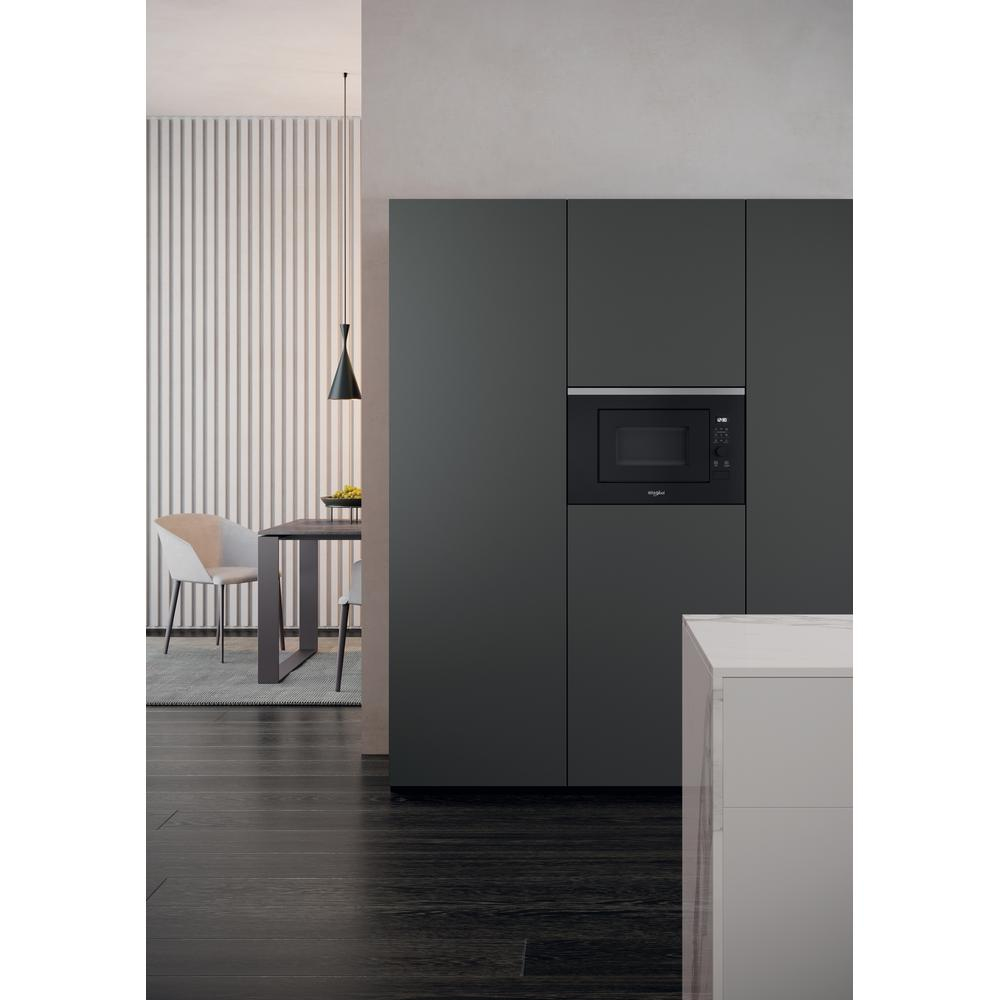 Modern kitchen with a dark gray built-in microwave. Table with chairs and a pendant light.
