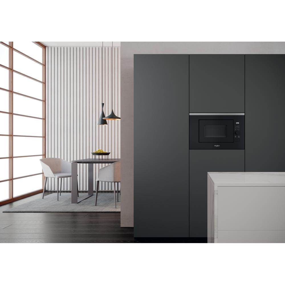 Kitchen scene with a microwave built into a dark cabinet and a table with chairs.