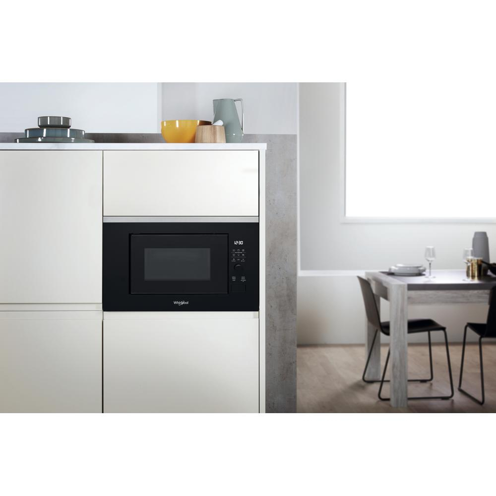 Black built-in microwave oven in a white cabinet in a kitchen setting.