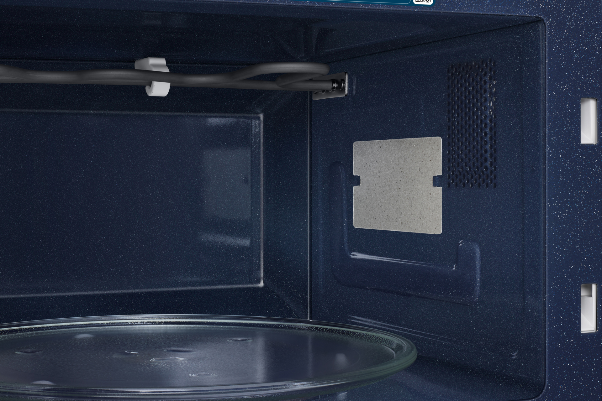 Wnętrze granatowej kuchenki mikrofalowej ze szklanym talerzem.