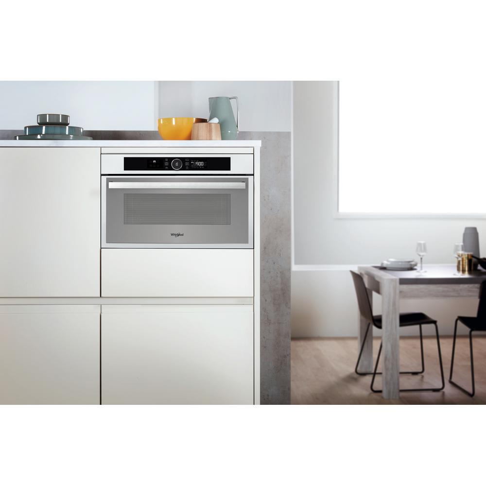 Un horno microondas Whirlpool blanco instalado en un armario de cocina. El horno está cerrado.