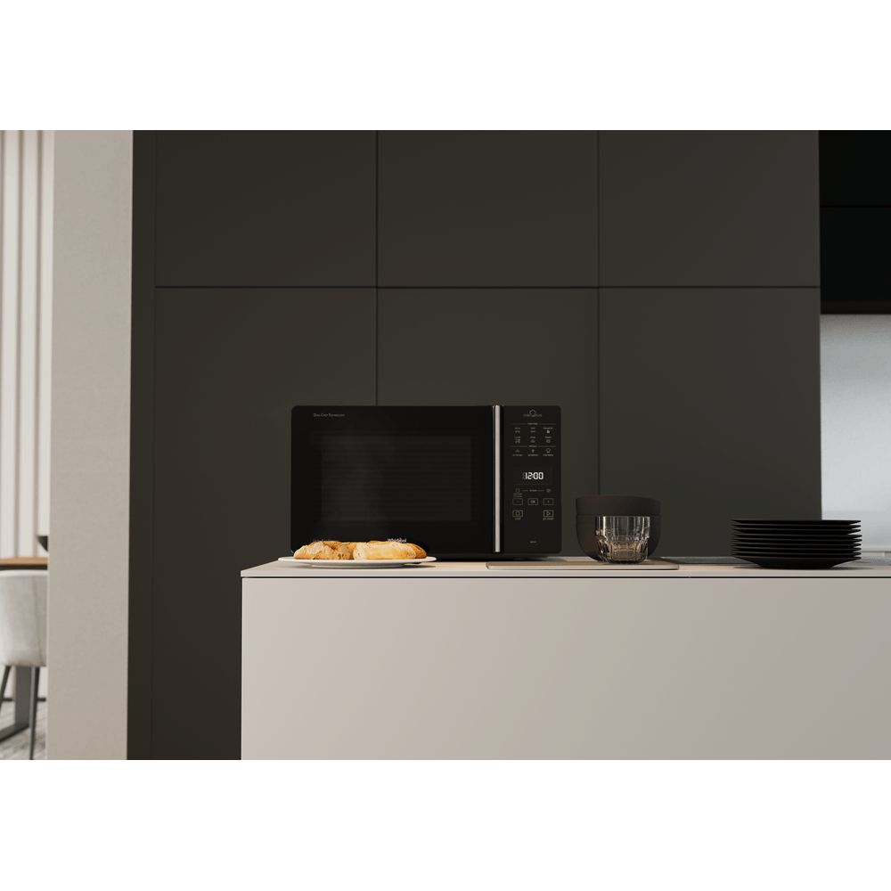Forno a microonde su un piano di lavoro, nero, con un piatto di cibo. Interni in bianco e nero.