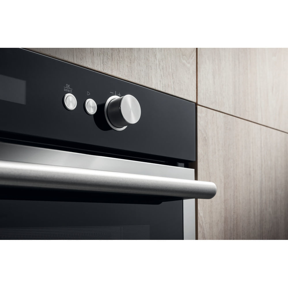 Primo piano del pannello di controllo di un forno con maniglia, pulsanti e un quadrante su una superficie in legno.