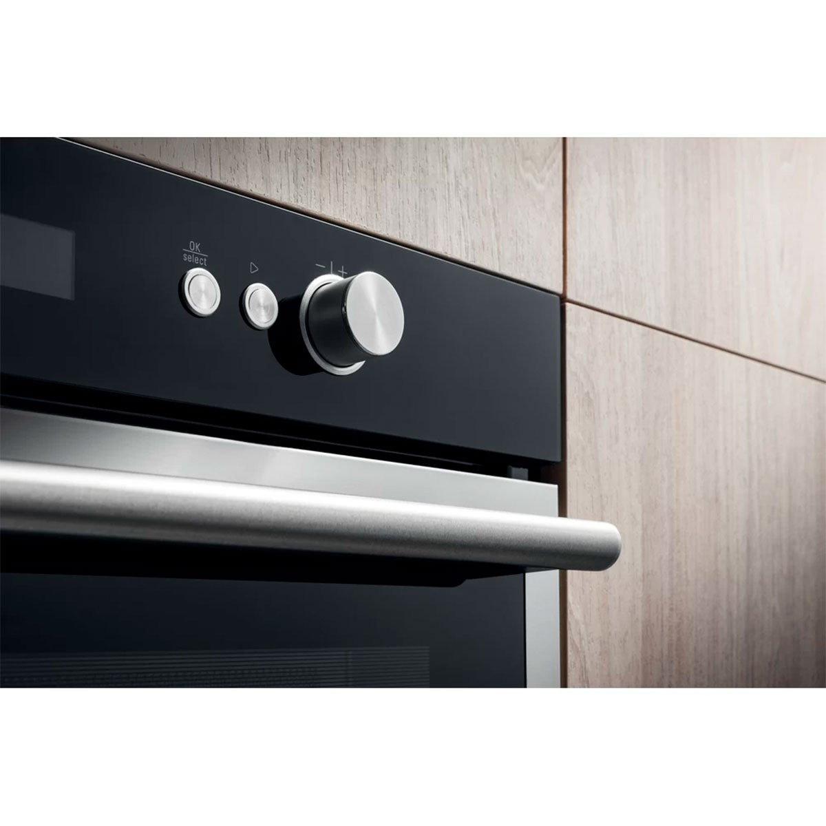 Primo piano di forno a microonde. Porta nera, pannello di controllo con manopole e maniglia. Sfondo in legno.