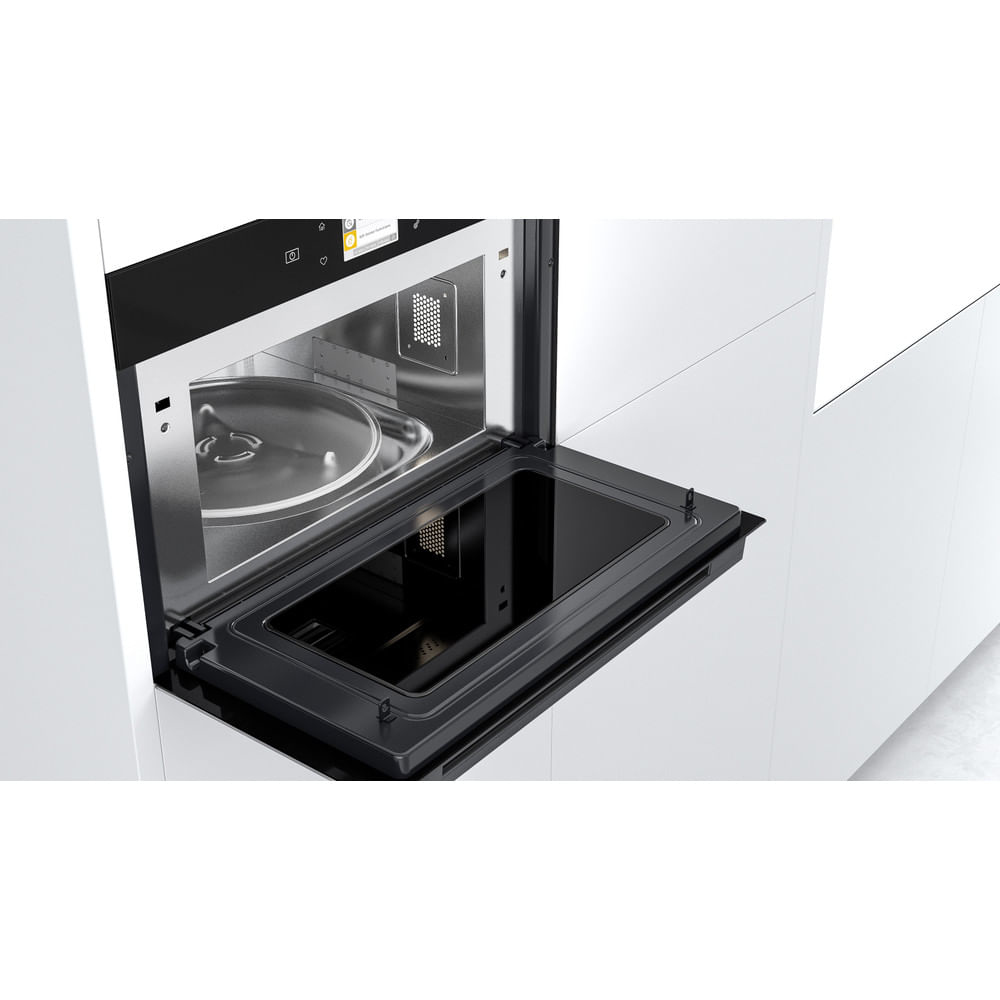 Un forno a microonde aperto che mostra l'interno con un piatto di vetro.