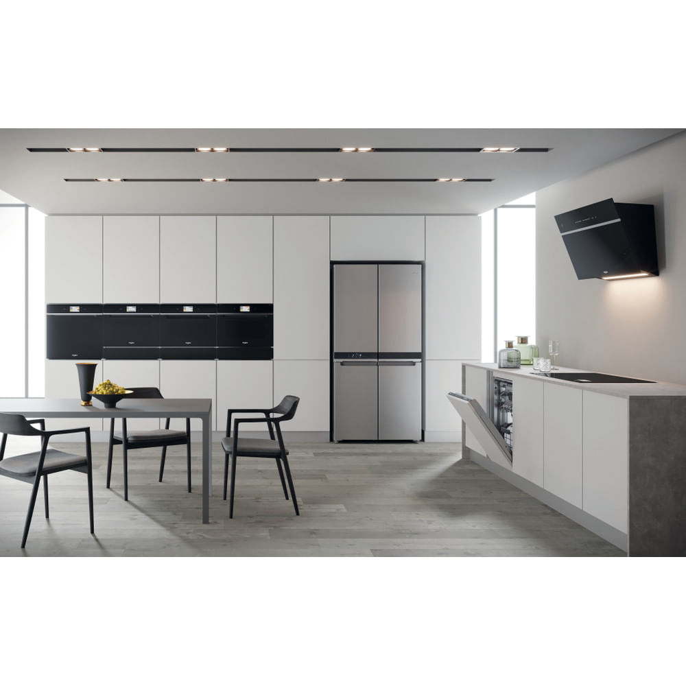 Cucina moderna con mobili bianchi, frigorifero in acciaio inox, tavolo da pranzo ed elettrodomestici neri.