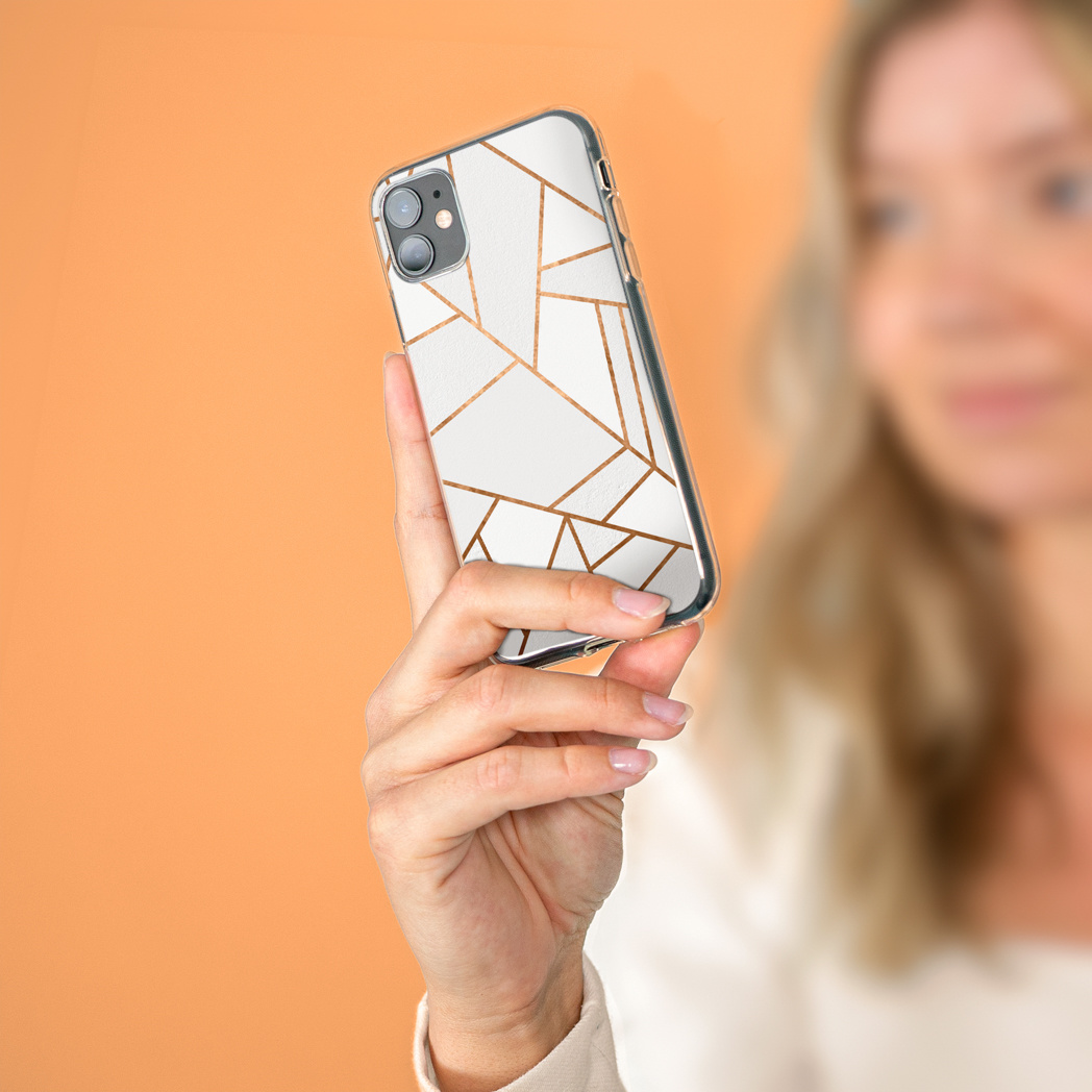 Een vrouw die een telefoon vasthoudt met een wit en goud geometrisch ontwerp.