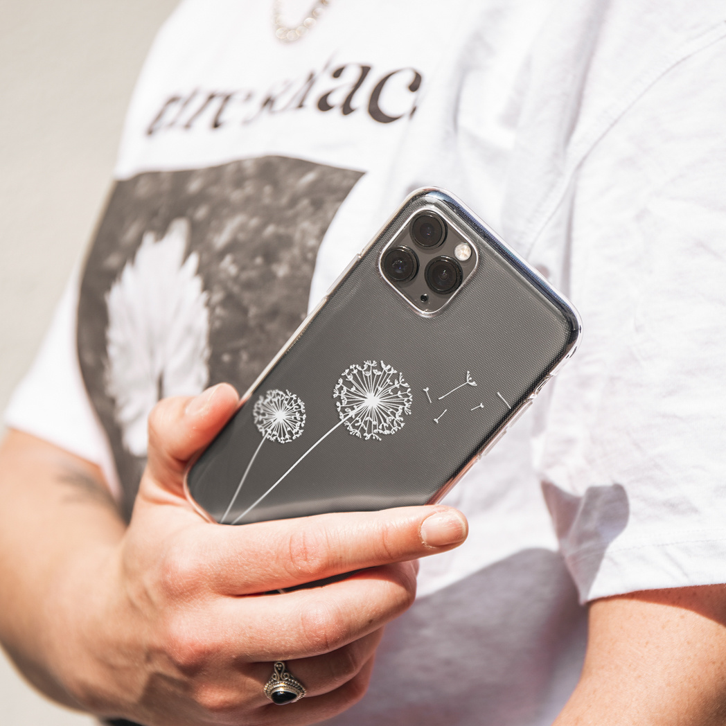 Una persona tiene in mano un telefono con una custodia trasparente con disegni di denti di leone.