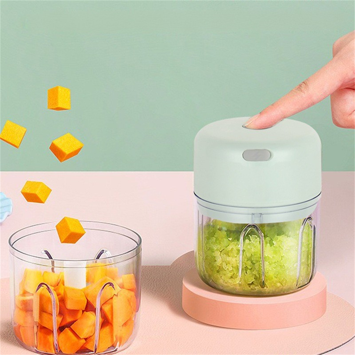 Ein kleiner grüner Food-Processor mit gehacktem Gemüse und orangefarbenen Würfeln in einer Schüssel.