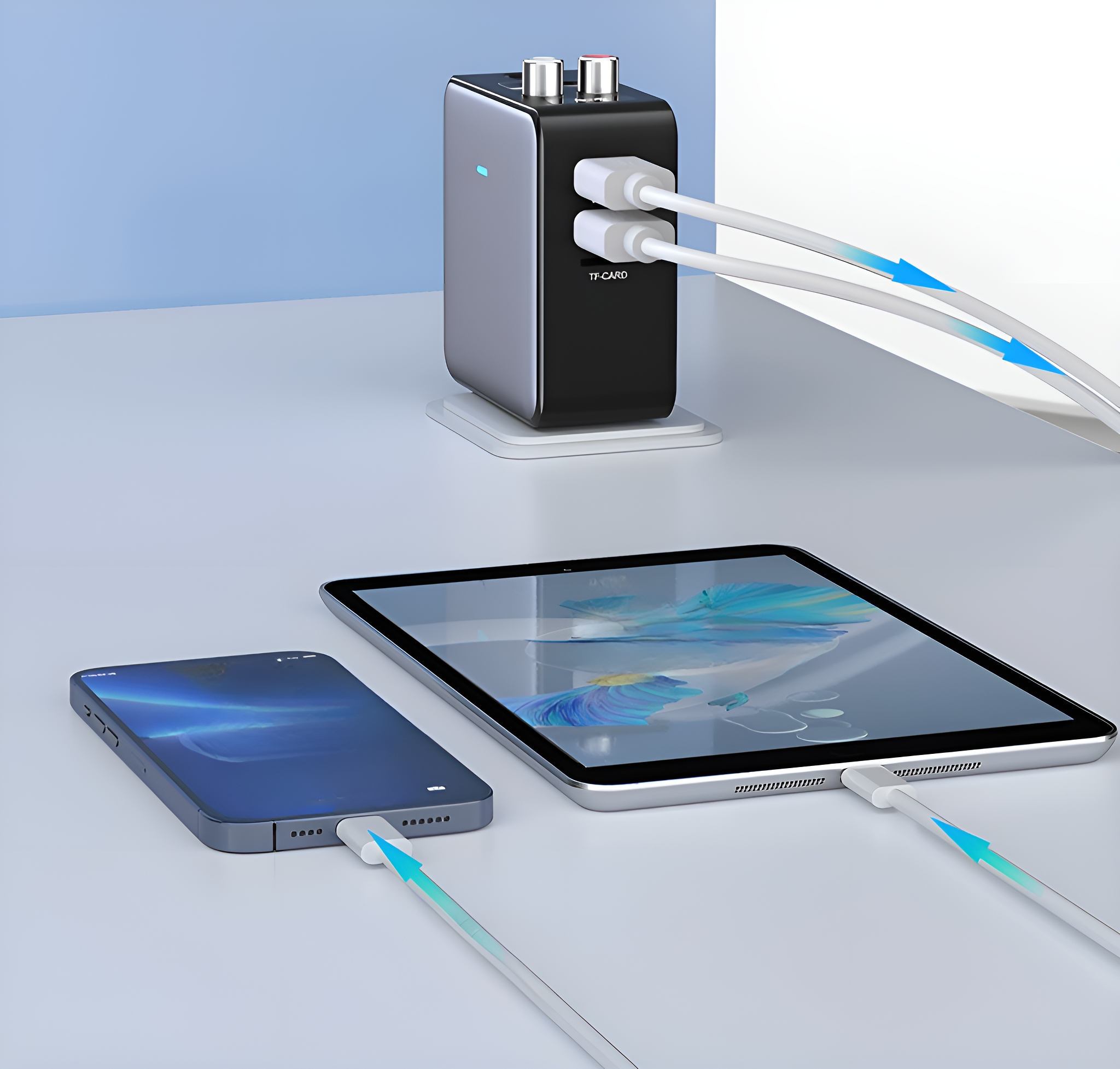 Ein schwarzes und silbernes Gerät mit USB-Kabeln, die mit einem Tablet und Telefon verbunden sind.