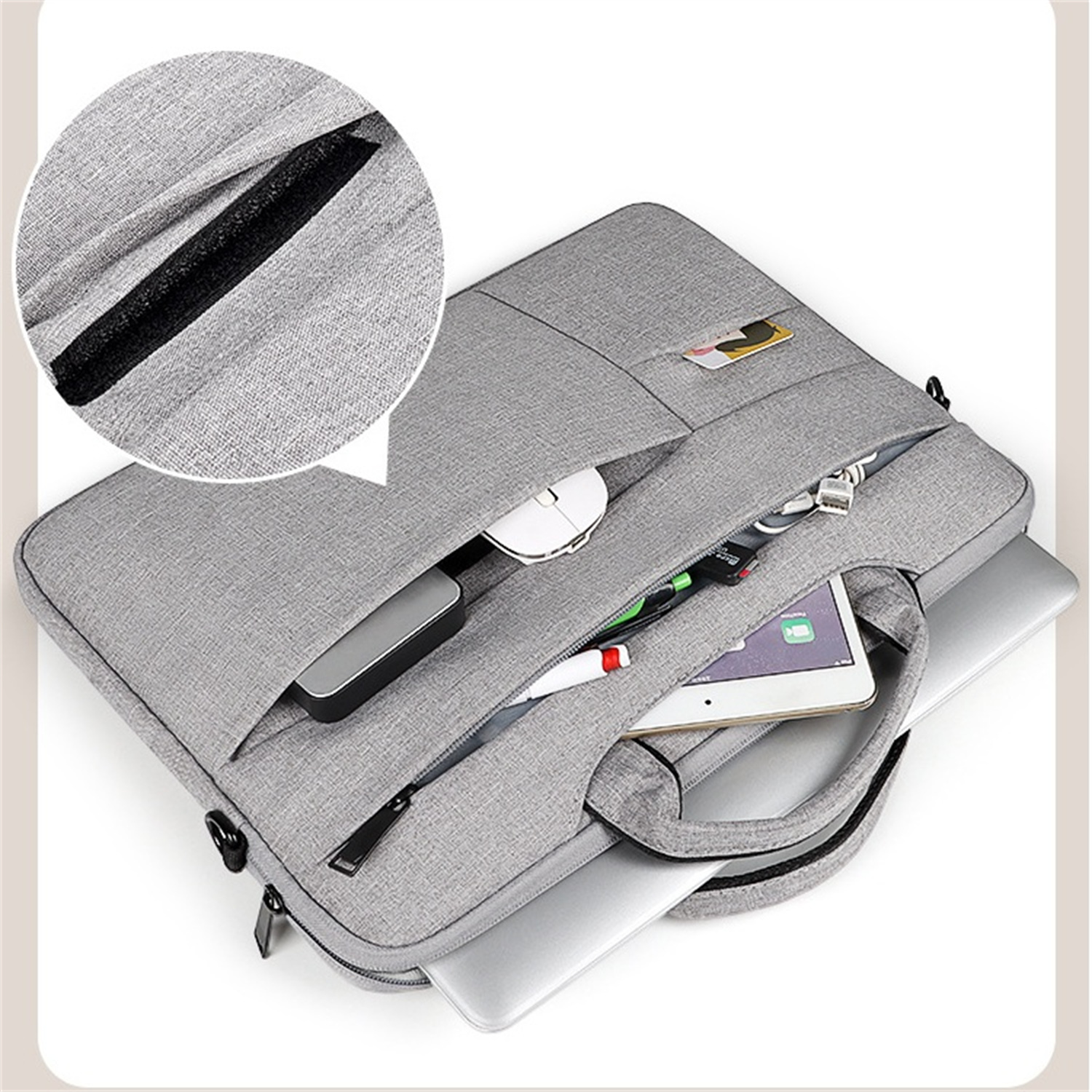 Graue Laptoptasche offen, Laptop, Maus und Zubehör sichtbar. Weißer Hintergrund.
