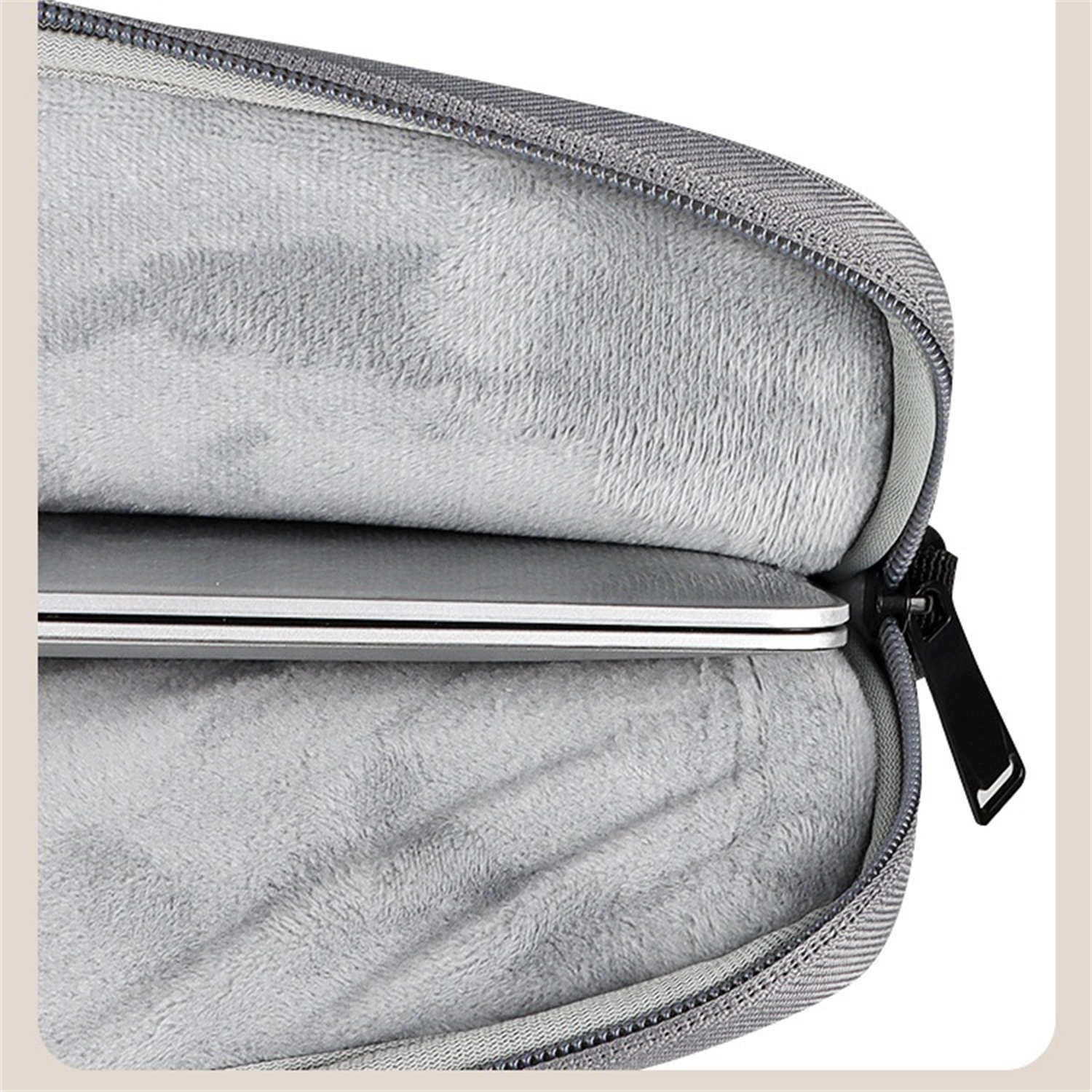 Eine graue Laptoptasche mit einem Laptop darin. Die Tasche hat einen Reißverschluss.