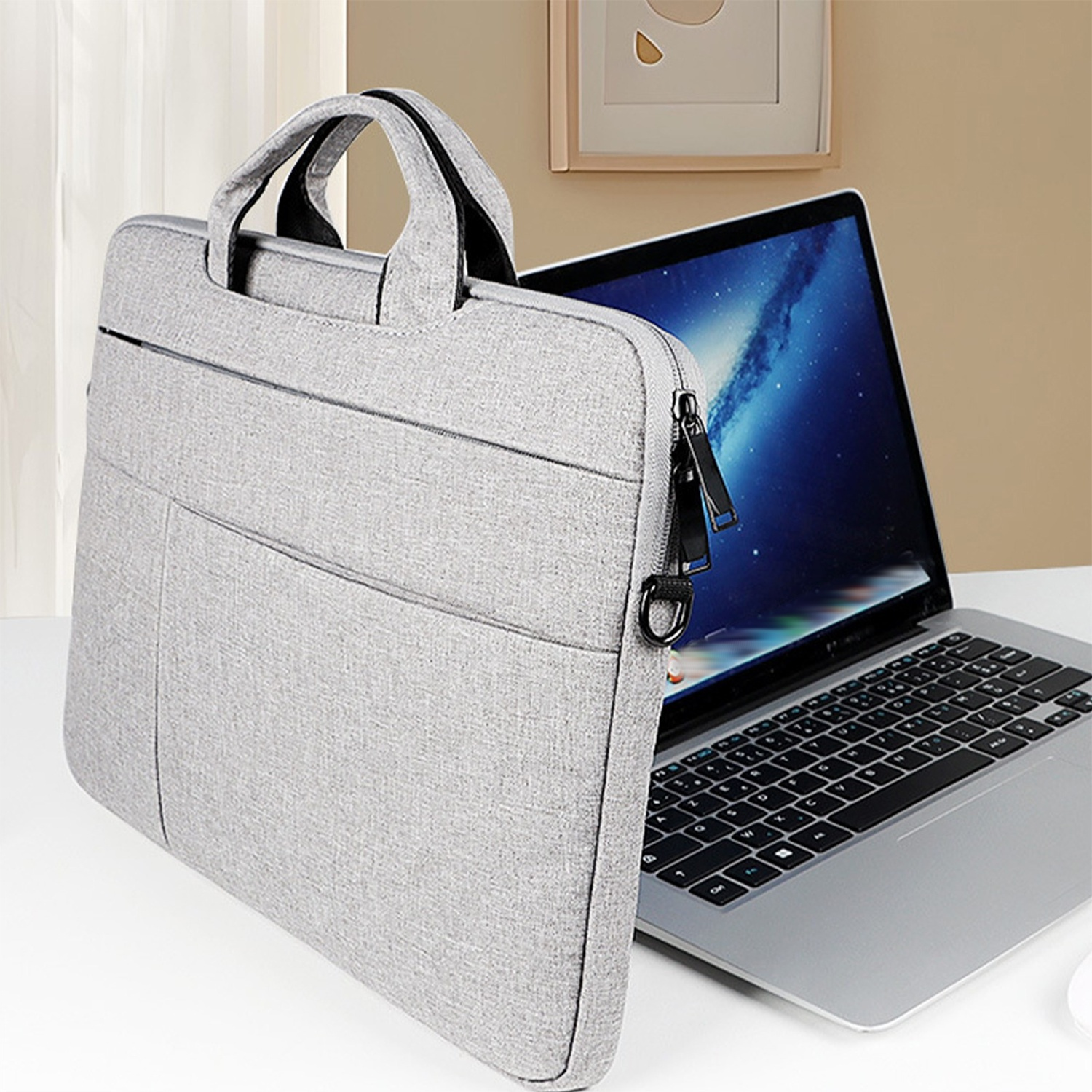 Eine graue Laptoptasche liegt auf einer weißen Oberfläche mit einem Laptop darin. Ein Laptop ist rechts geöffnet.
