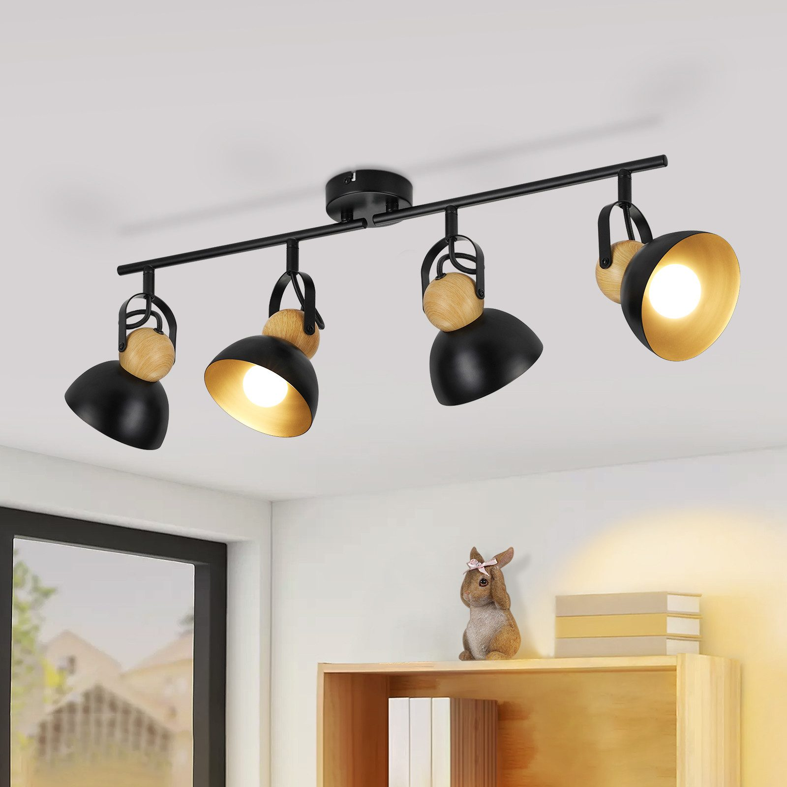 Schwarze Schienenbeleuchtung mit vier Lampen. Jede Lampe hat einen schwarzen Schirm, Holzdetails und Gold innen.