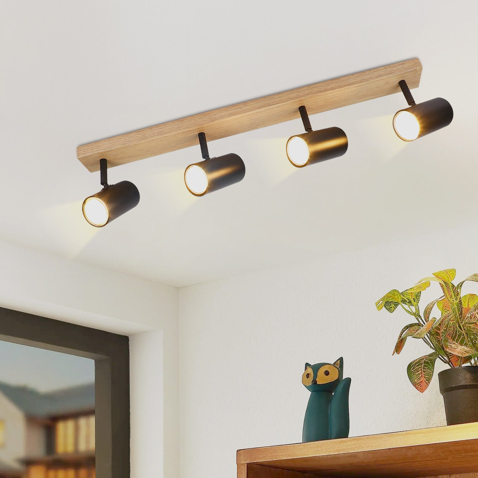 Quattro faretti neri su una trave di legno sono montati sul soffitto.