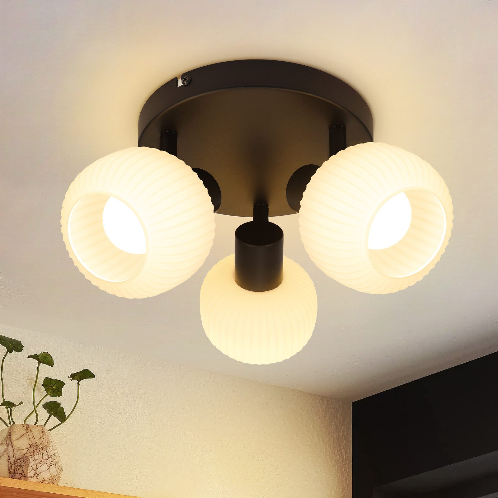 Lampada da soffitto con tre luci a forma di globo. Ogni globo ha una texture a coste ed emette luce.