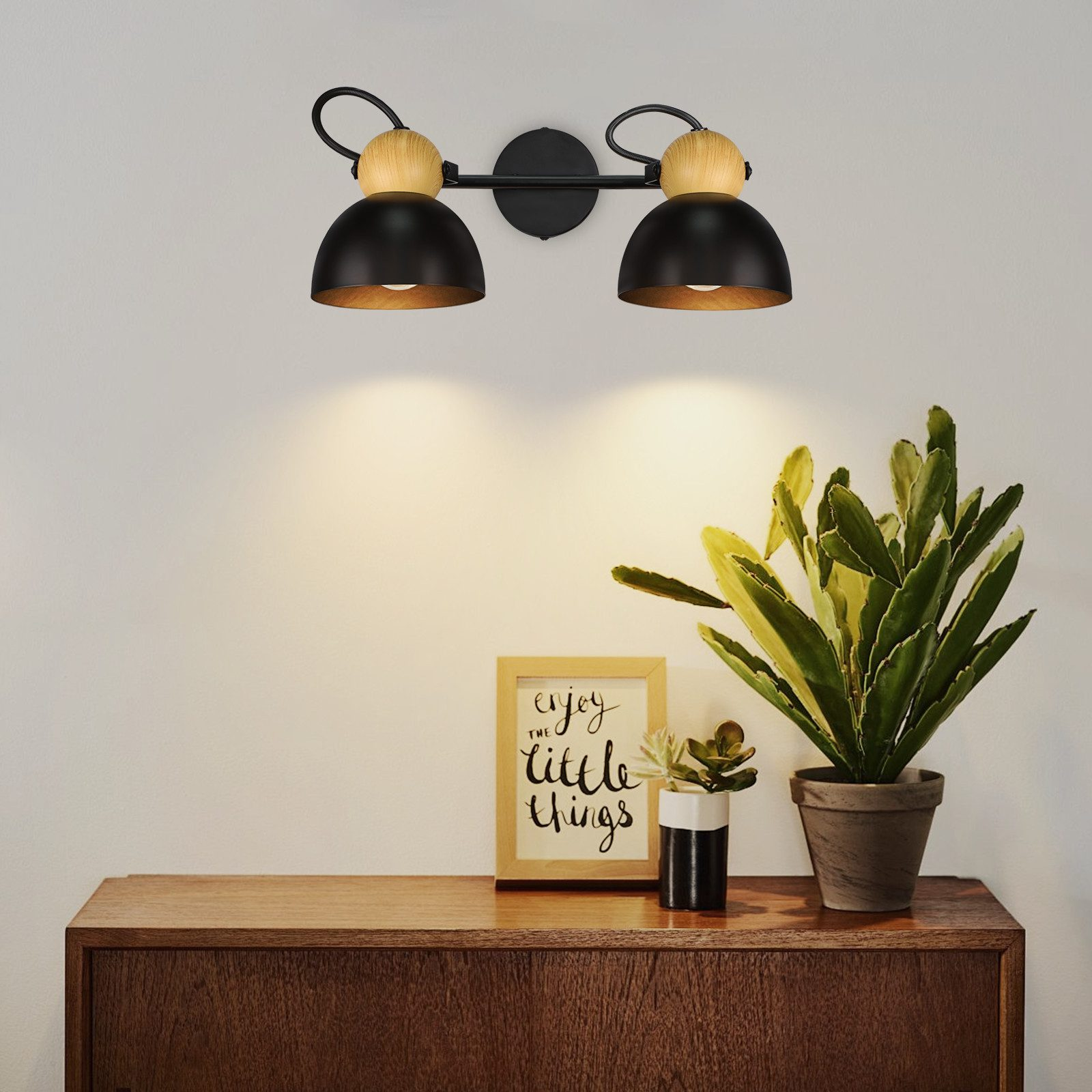 Lampa ścienna z dwoma czarnymi kloszami z drewnianym akcentem. Roślina i obraz w ramce.