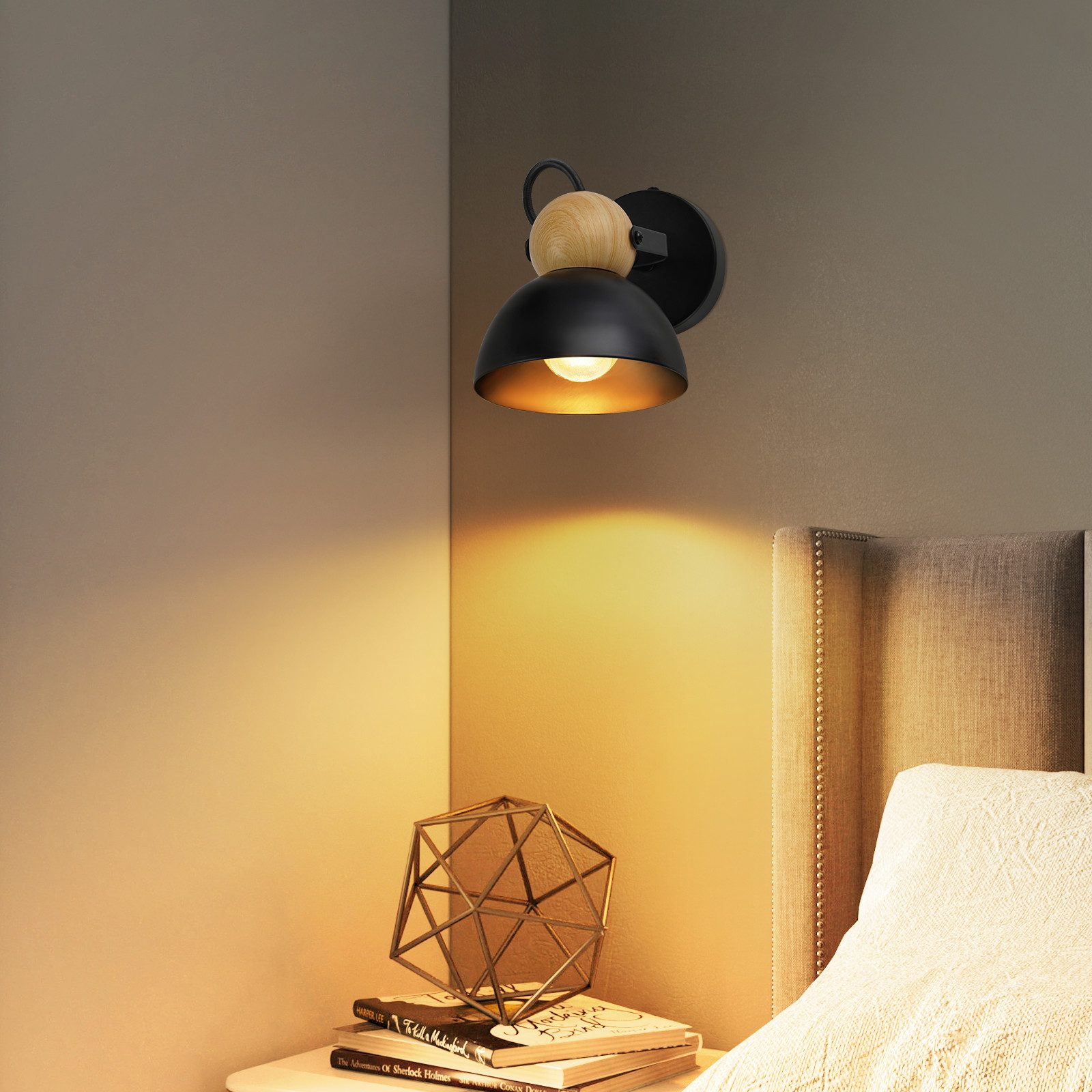 Una lampada da parete nera con un accento in legno, che proietta una luce calda su un letto.