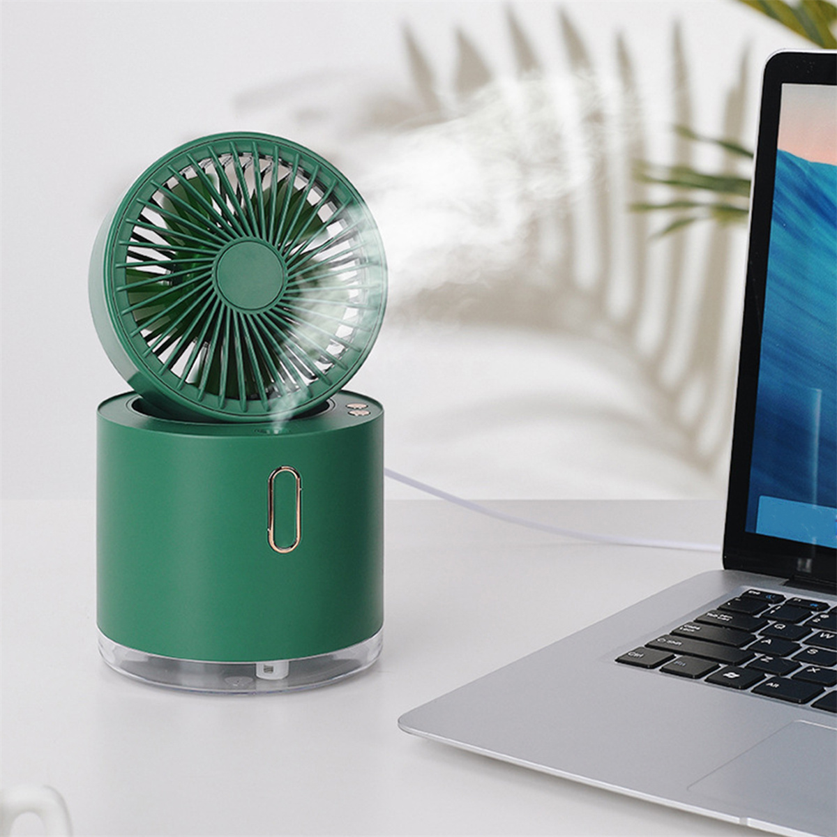 Grüner Mini-Ventilator und Luftbefeuchter auf weißem Tisch, mit Laptop.