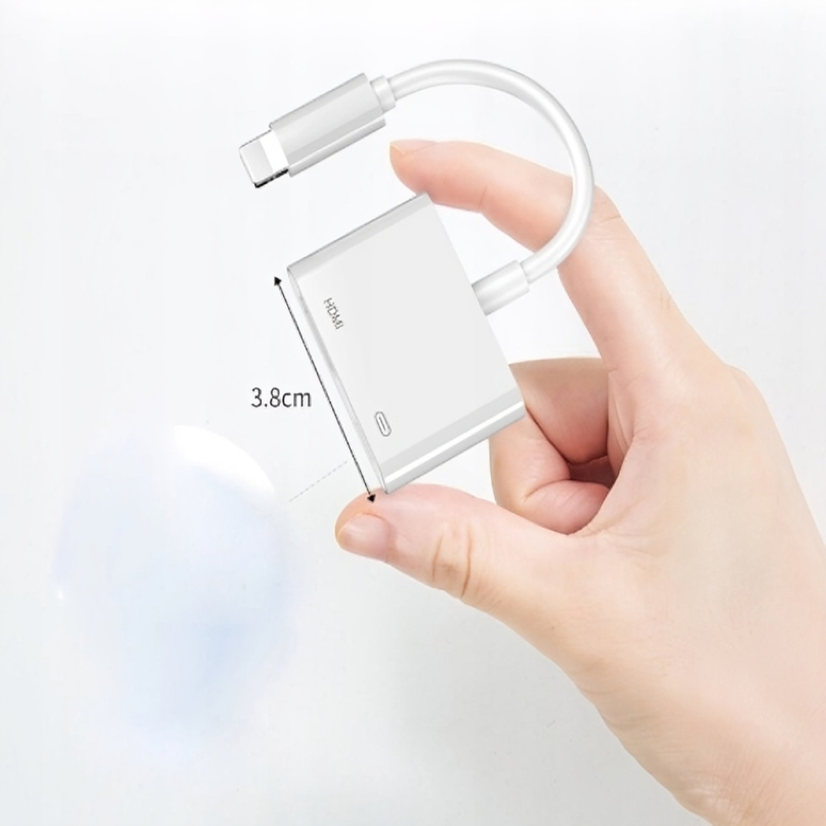 Biała przejściówka HDMI ze złączem USB-C. Trzyma ją ręka. Pokazano pomiar 3,8 cm.