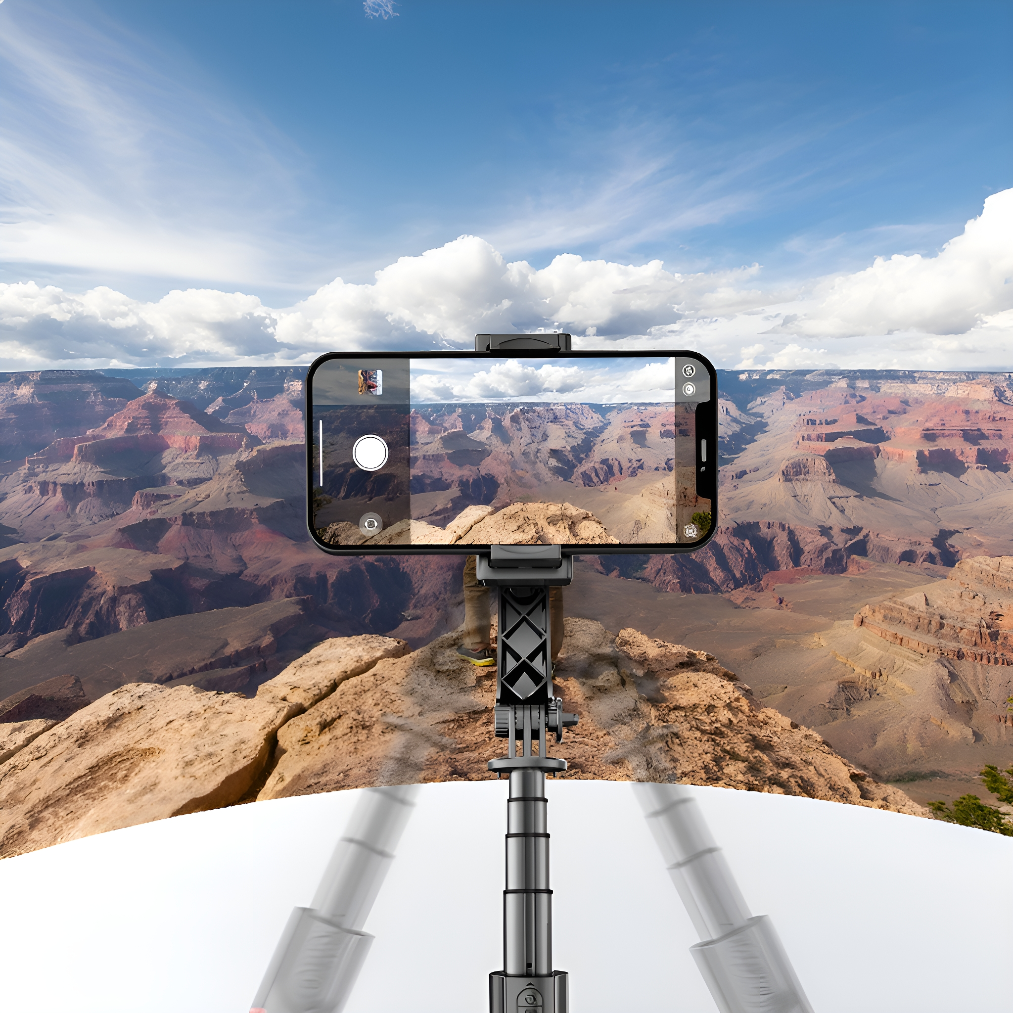 Ein Telefon auf einem Selfie-Stick zeigt einen Canyon, mit einem bewölkten Himmel über einer felsigen Landschaft.