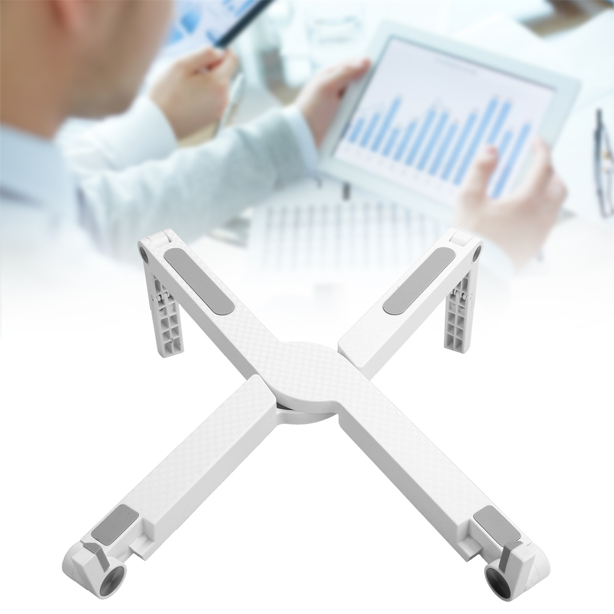 Ein faltbarer, weißer Laptopständer in X-Form. Im Hintergrund ist eine Person zu sehen, die ein Tablet benutzt.