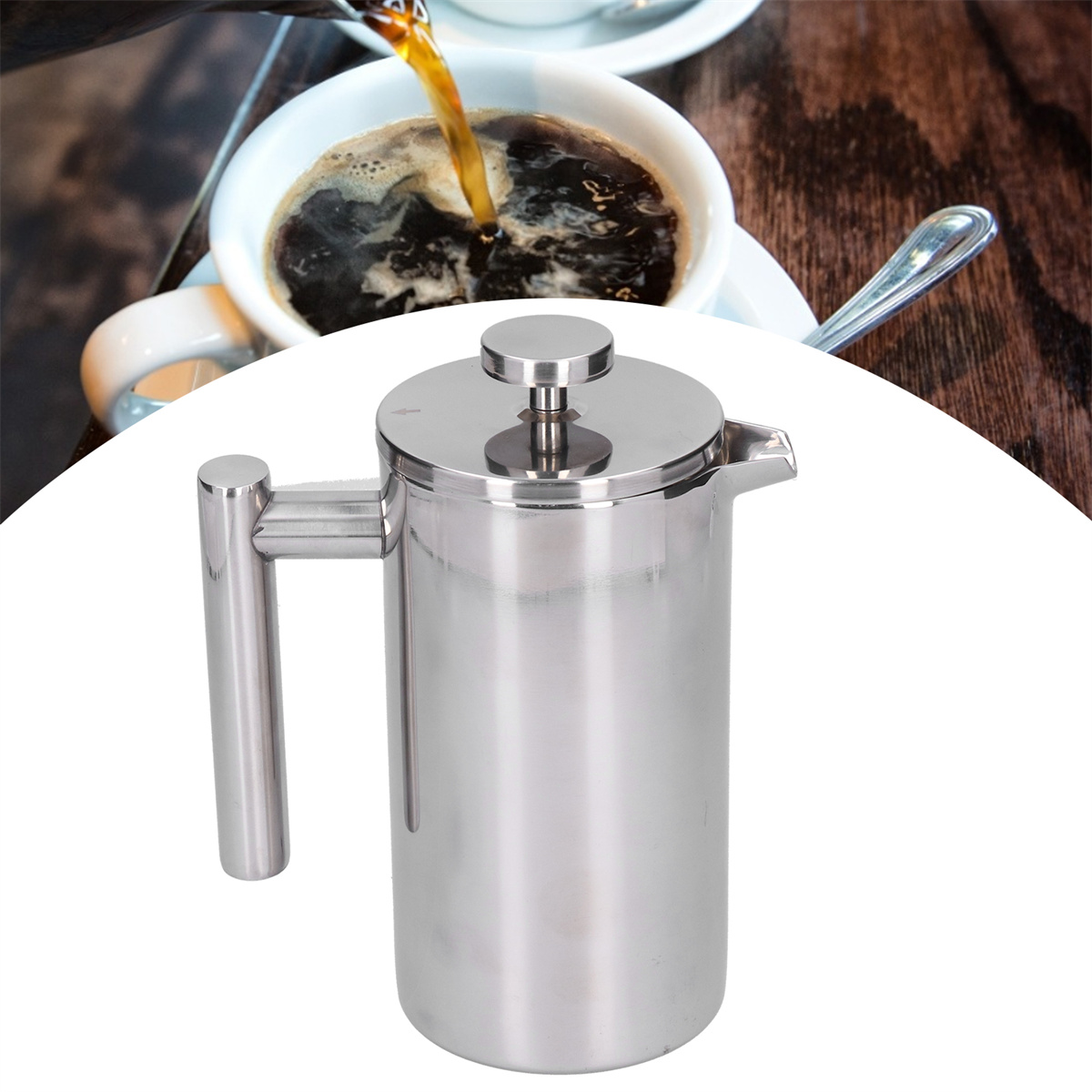 Eine French Press aus Edelstahl, Kaffee wird in eine Tasse gegossen. Ein Löffel liegt auf einer Untertasse im Hintergrund.