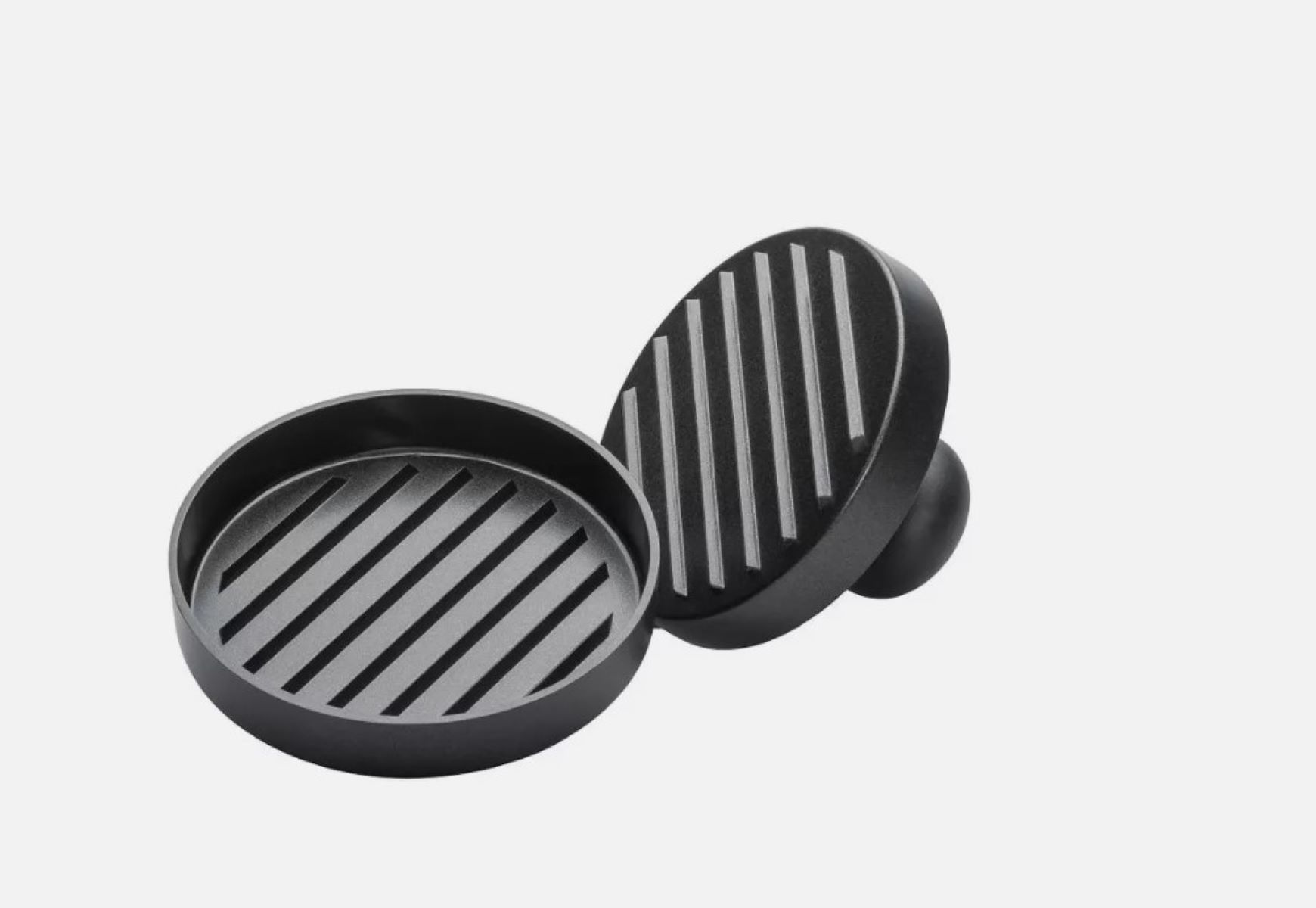 Eine schwarze Burgerpresse mit rundem Boden und Oberteil. Die Presse hat Grilllinien.