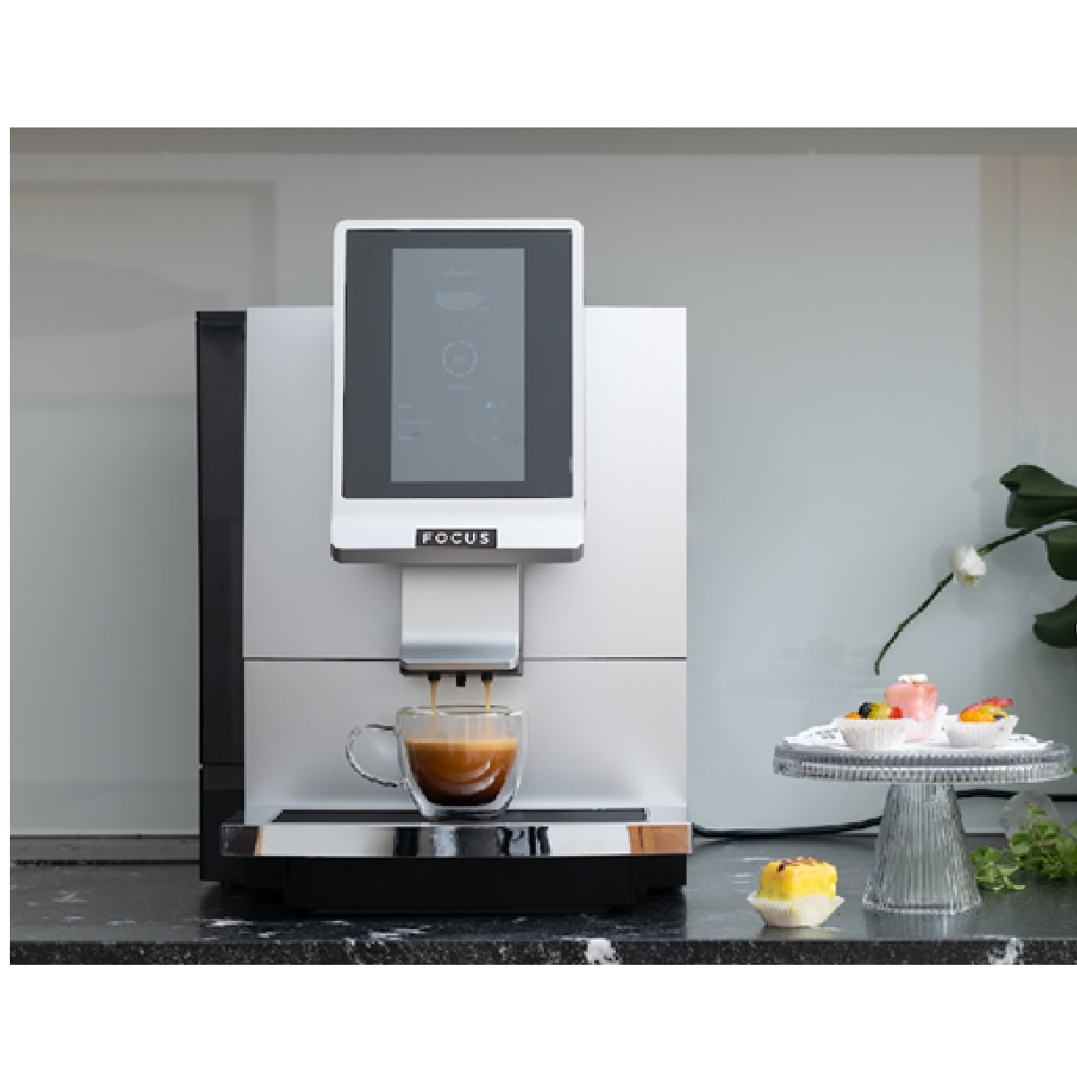 Moderne Kaffeemaschine mit Display und Tasse, serviert Kaffee neben Desserts.