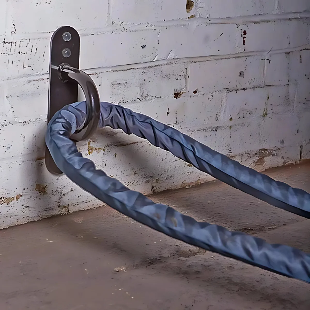 A metal chain is secured to a wall with a metal bracket.