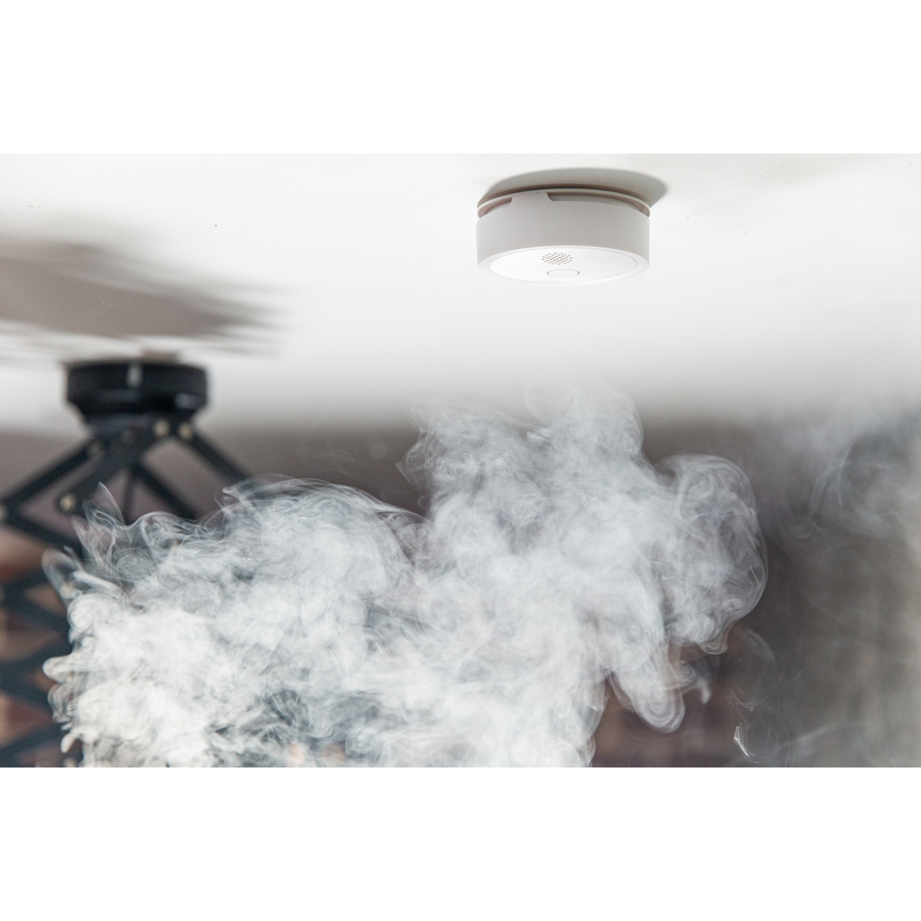 Czujnik dymu na suficie, z dymem unoszącym się poniżej.
